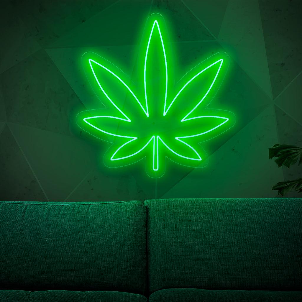 Ein beleuchtetes Neonschild mit einem Marihuanablatt, das Cannabis und die Graskultur symbolisiert und jedem Raum einen Hauch von Kräutercharme verleiht