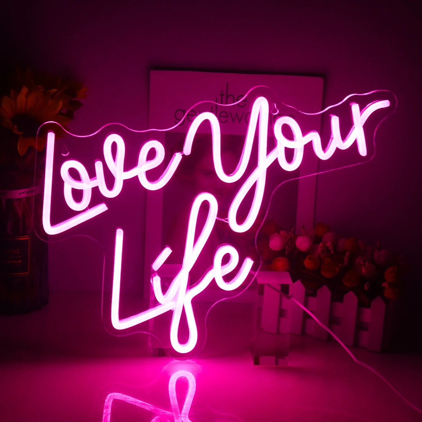 Ein hell erleuchtetes LED-Neonschild mit den Worten „Love Your Life“ in stilvoller Schreibschrift.