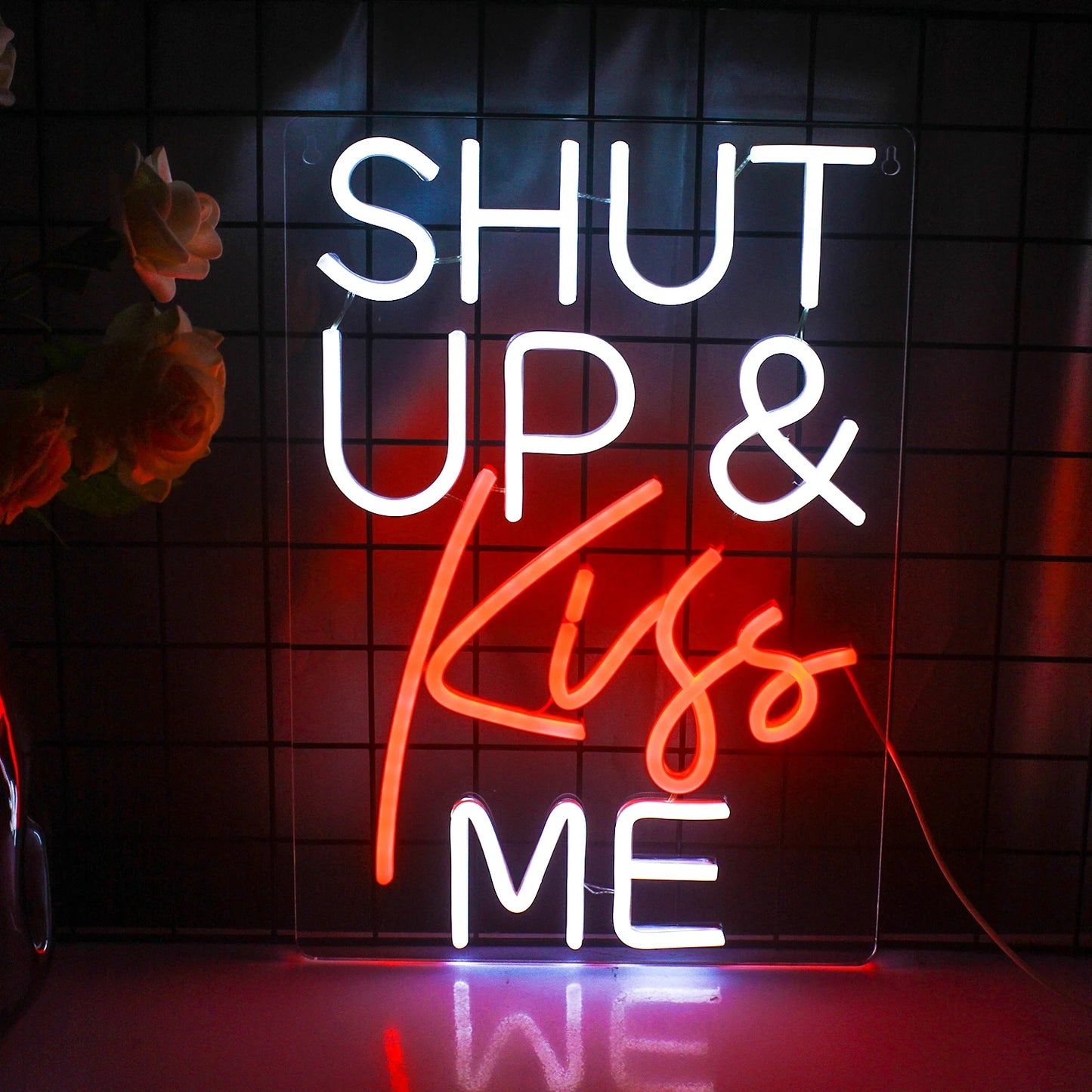 Das Bild zeigt ein leuchtendes LED-Neonschild mit den Worten „Shut Up Kiss Me“ in einer verspielten, kursiven Schrift.