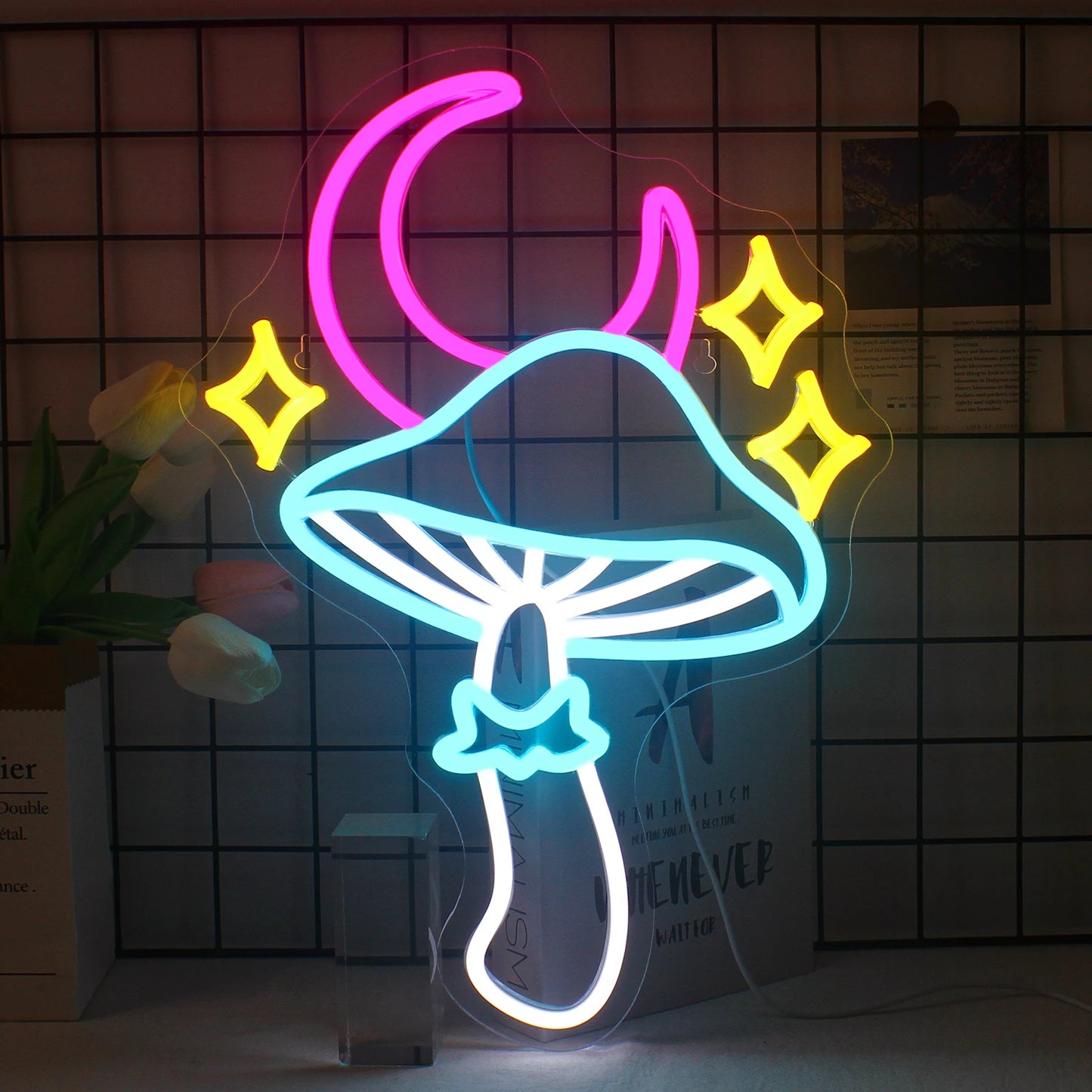 Das Bild zeigt ein leuchtendes LED-Neonschild mit einem skurrilen Design aus Stern, Mond und Pilz.