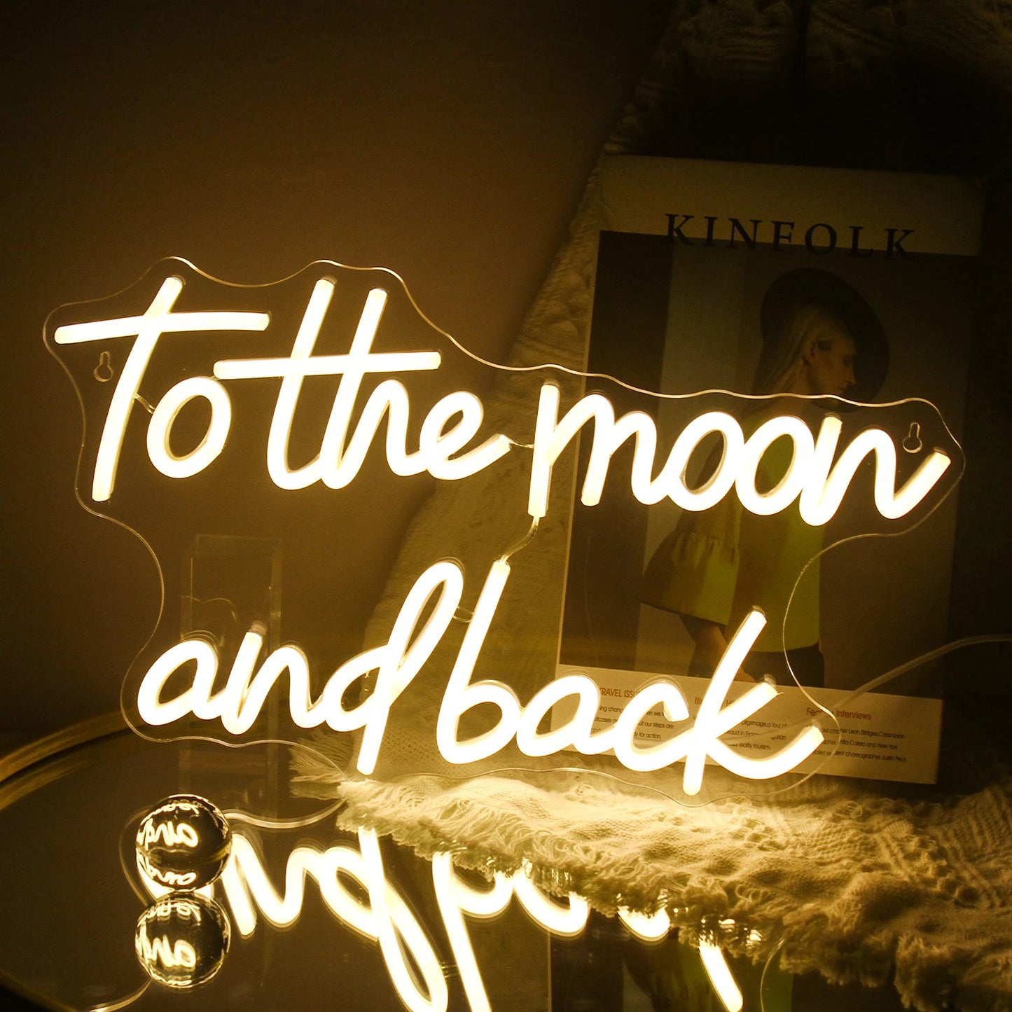 Das Bild zeigt ein handgefertigtes LED-Neonschild mit dem Satz „To The Moon And Back“ in eleganter, kursiver Schrift.