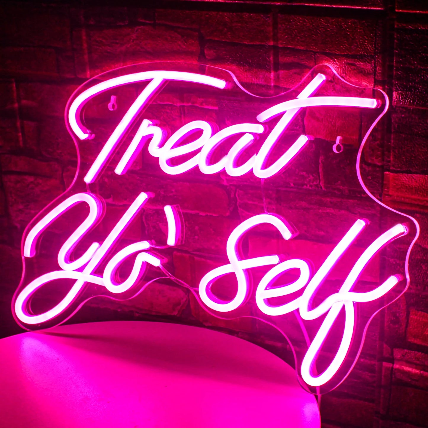 Das Bild zeigt ein leuchtendes LED-Neonschild mit den Worten „Treat Yo‘ Self“ in einer stilvollen Schreibschrift.