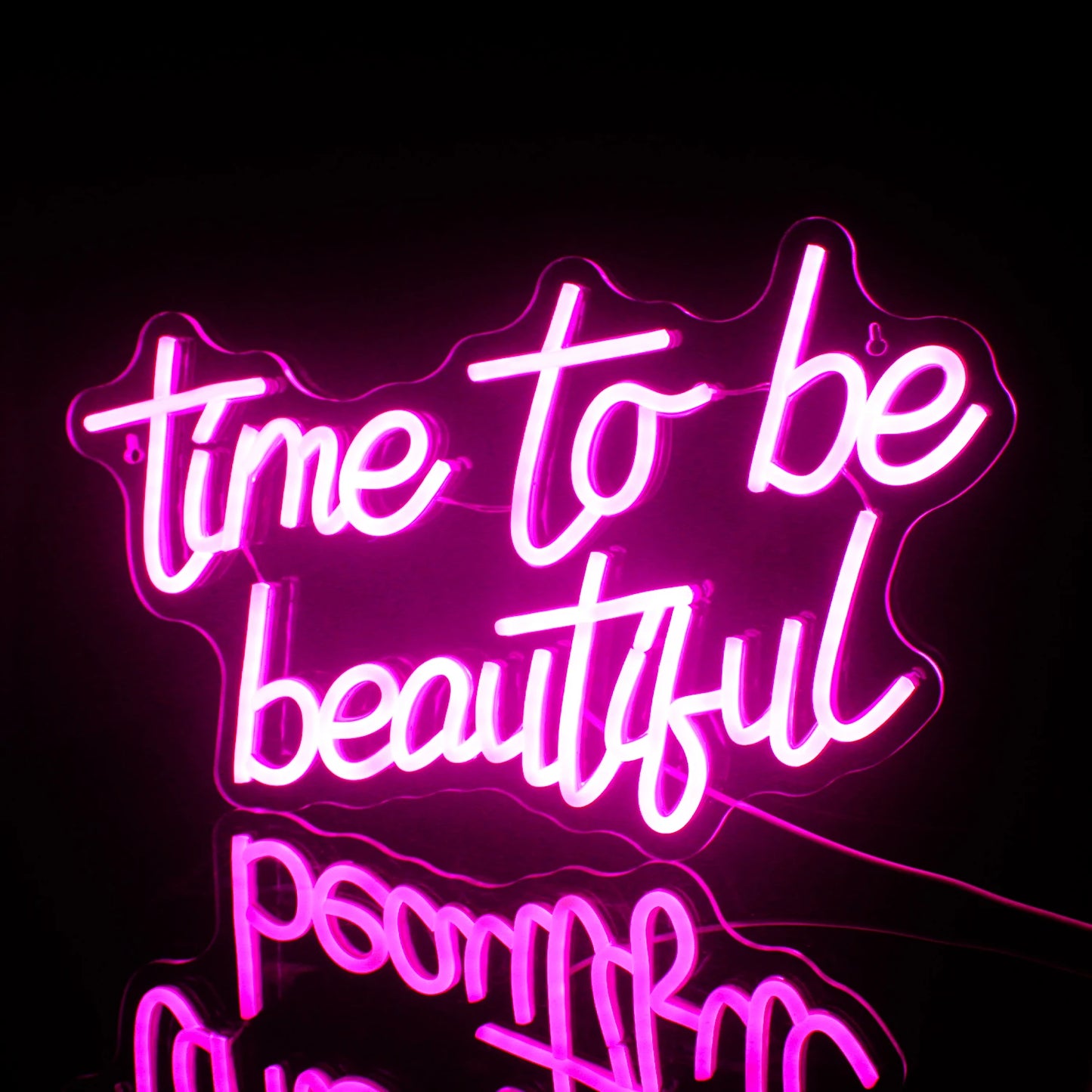 Ein leuchtendes LED-Neonschild mit der Aufschrift „Time to be Beautiful“ vor einer minimalistischen dunkelgrauen Wand.