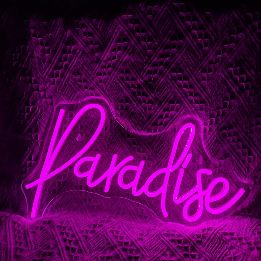 Das Bild zeigt ein lebendiges, handgefertigtes LED-Neonschild, auf dem in einer verspielten Schreibschrift das Wort „Paradise“ steht.