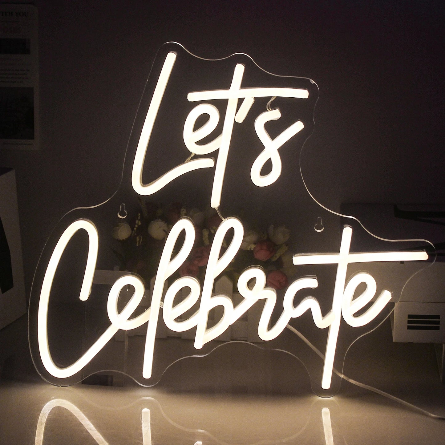 Das Bild zeigt ein leuchtendes LED-Neonschild mit der Aufschrift „Let’s Celebrate“.