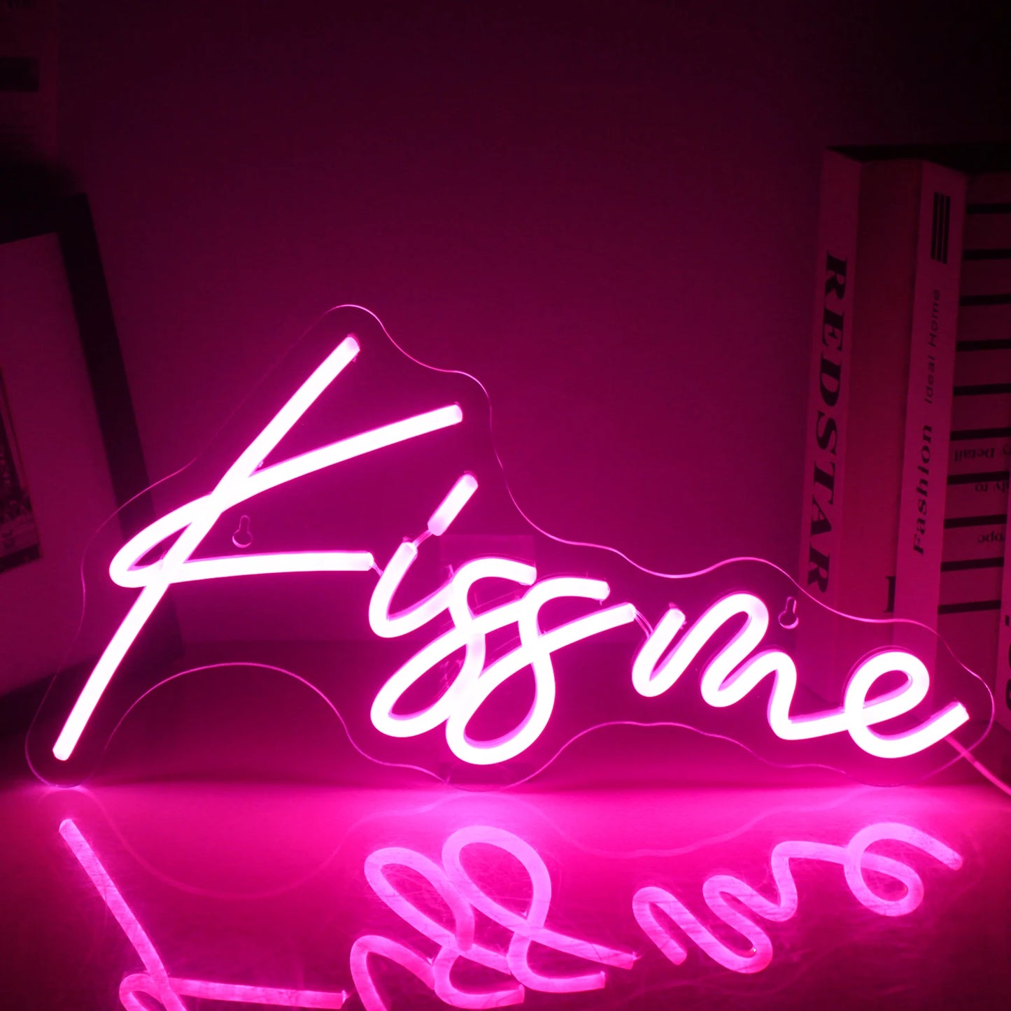Ein leuchtendes LED-Neonschild mit der Aufschrift „Kiss Me“ leuchtet und zeigt einen hellen und kräftigen rosa Schriftzug auf dunklem Hintergrund.