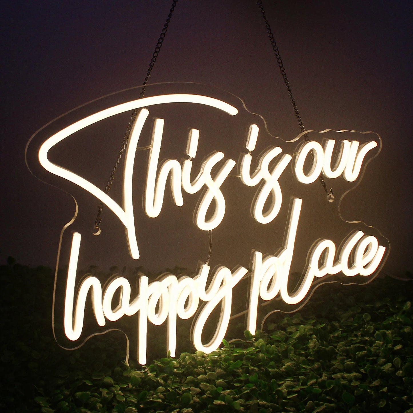 Das Bild zeigt ein leuchtendes LED-Neonschild mit den Worten „This is our happy place“ in Schreibschrift.