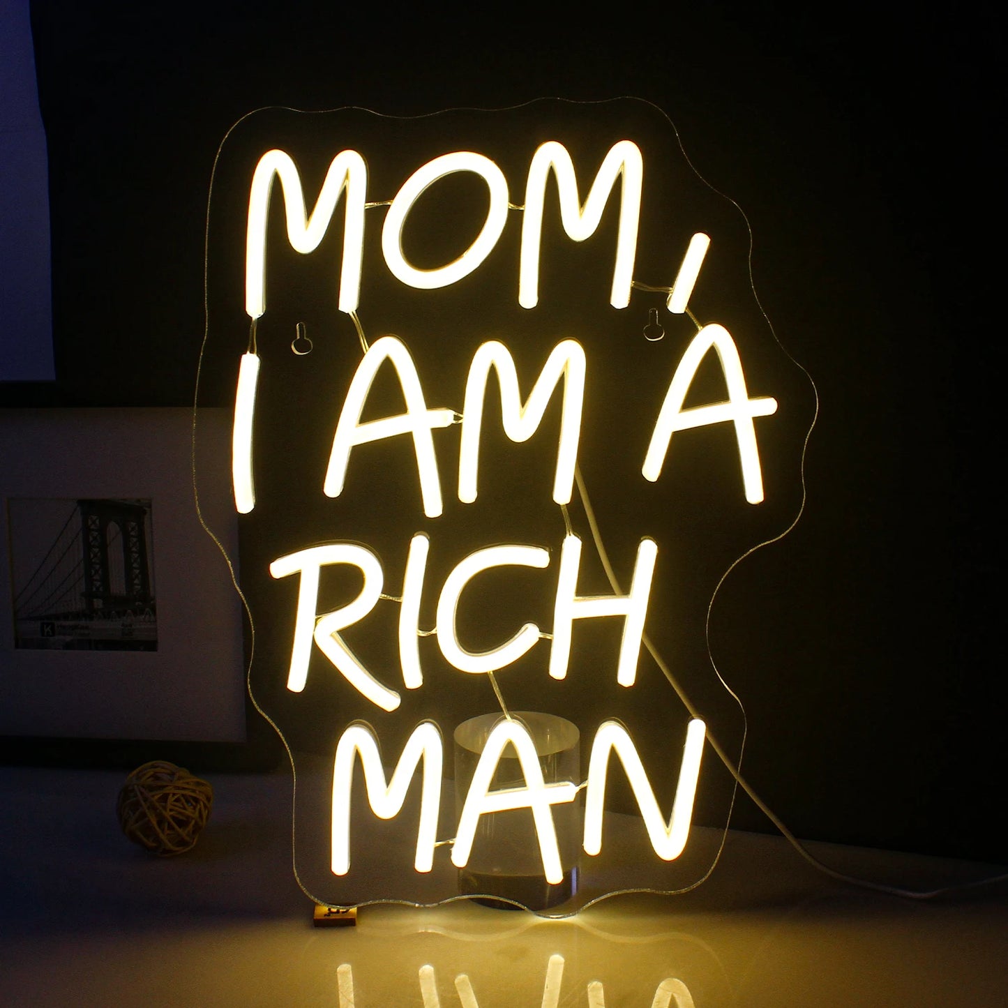 Ein leuchtendes LED-Neonschild mit dem Satz „Mom, ich bin ein reicher Mann“ in eleganter Schreibschrift.