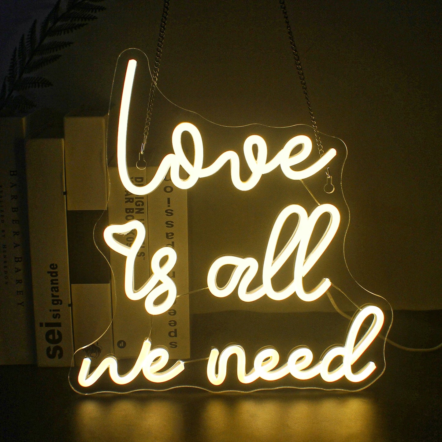 Das Bild zeigt ein leuchtendes LED-Neonschild mit der Aufschrift „Love is all we need“ in fließender Schreibschrift.