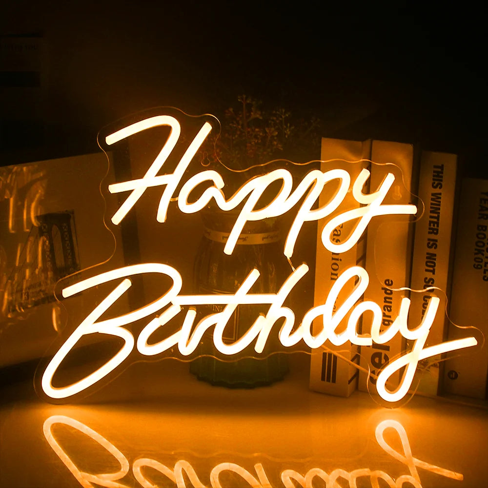Vor einem dunklen Hintergrund leuchtet ein leuchtendes LED-Neonschild mit der Aufschrift „Happy Birthday“.