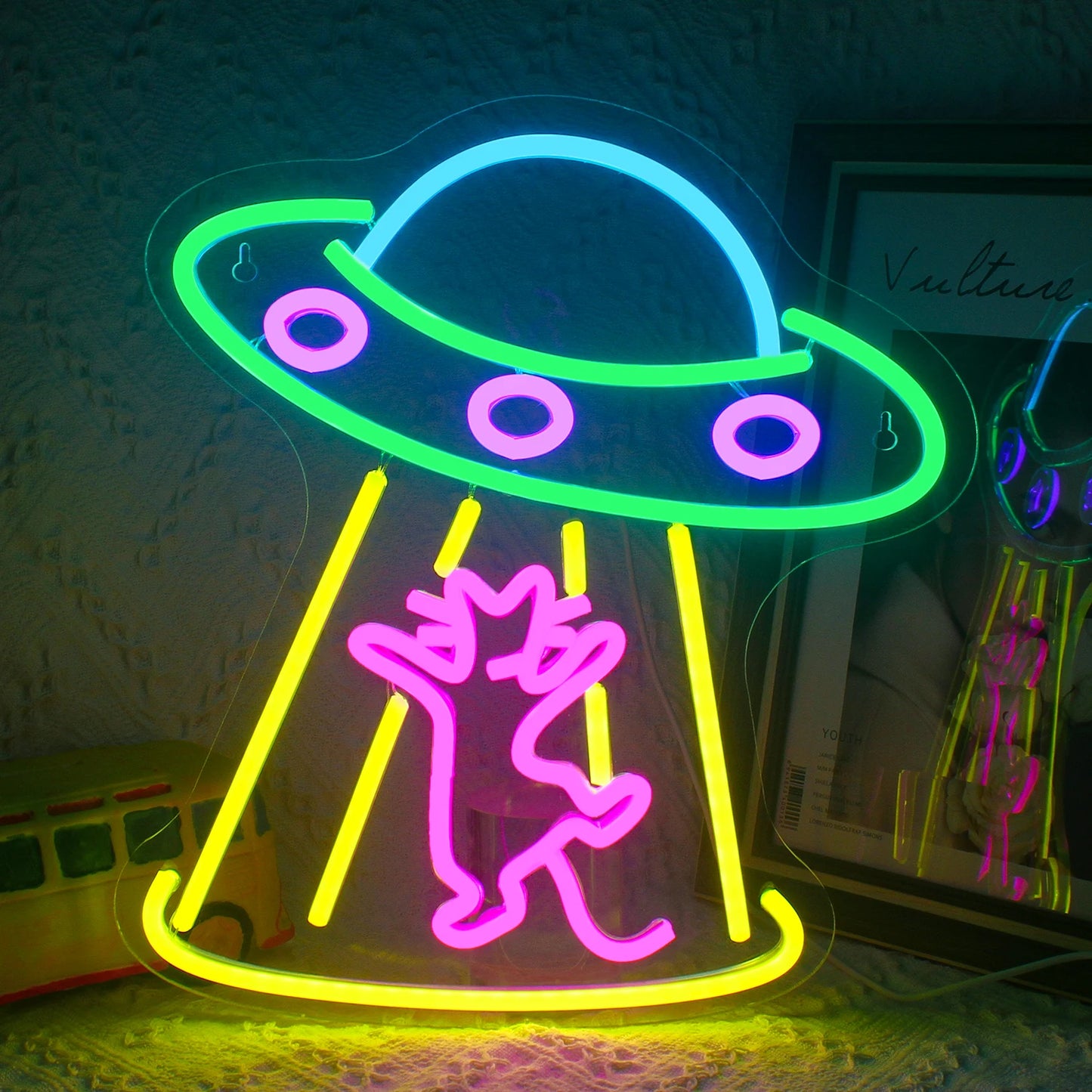 Das Bild zeigt ein leuchtendes LED-Neonschild in Form eines Raumschiffs.