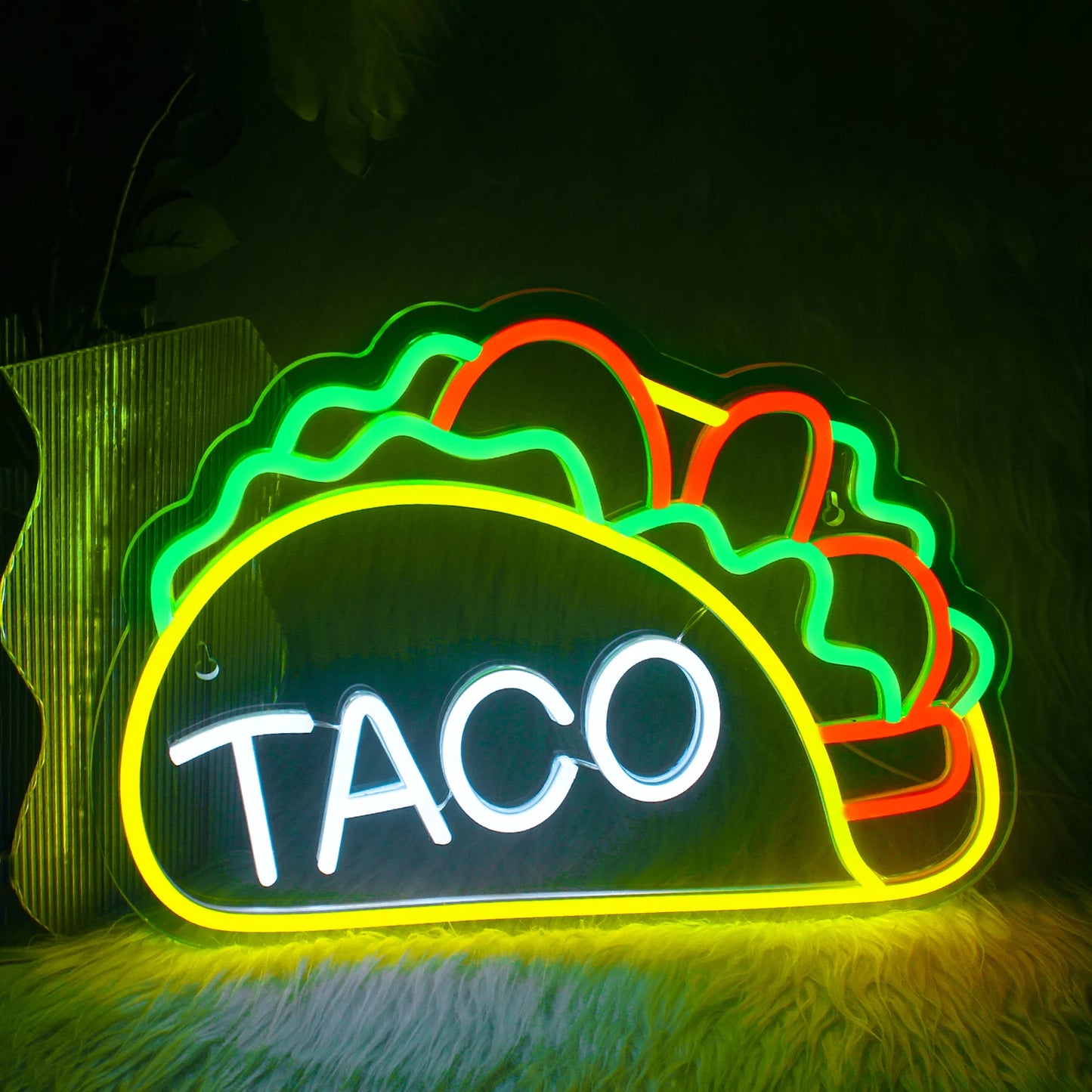 Das Bild zeigt ein leuchtendes LED-Neonschild in der Form, die das Wort „Tacos“ buchstabiert.