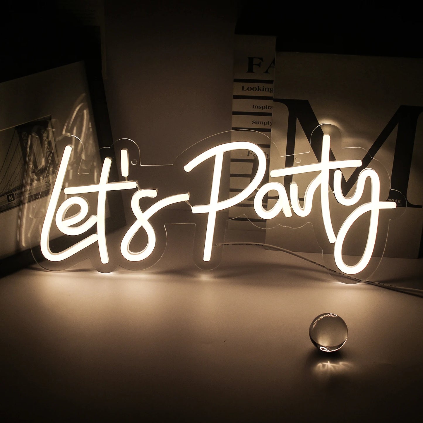 Es wird ein leuchtendes LED-Neonschild mit der Aufschrift „Let’s Party“ angezeigt, das in fetter, kursiver Schrift erscheint.