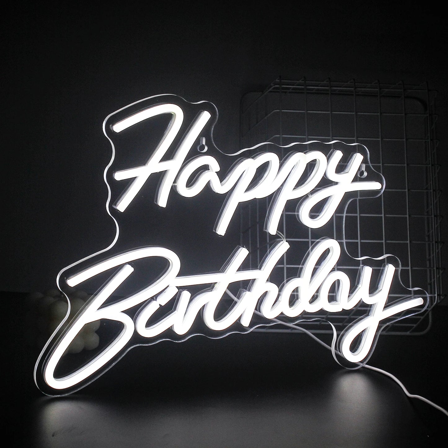 Ein leuchtendes LED-Neonschild mit der Aufschrift „Happy Birthday“, das warm vor einem dunklen Hintergrund leuchtet.