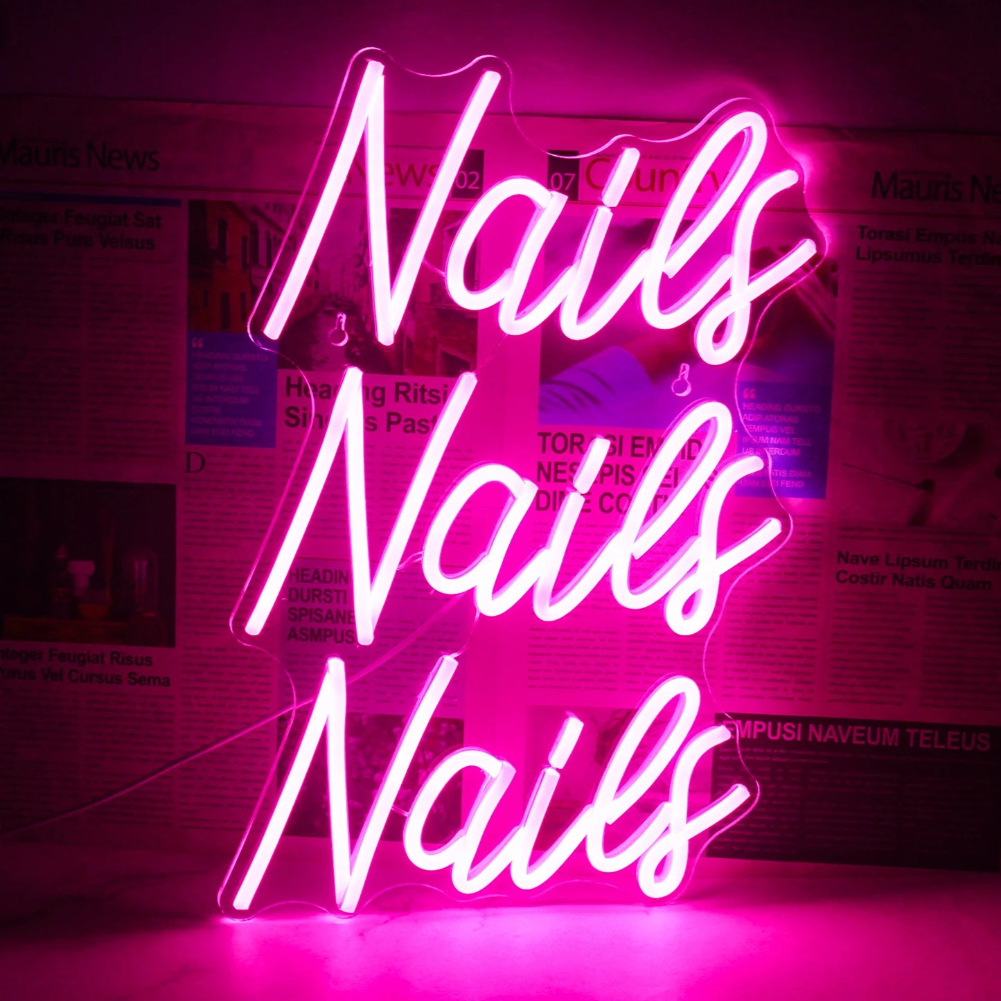 Das Bild zeigt ein leuchtendes und auffälliges LED-Neonschild, auf dem das Wort „Nails“ in einer stilvollen Schreibschrift steht.