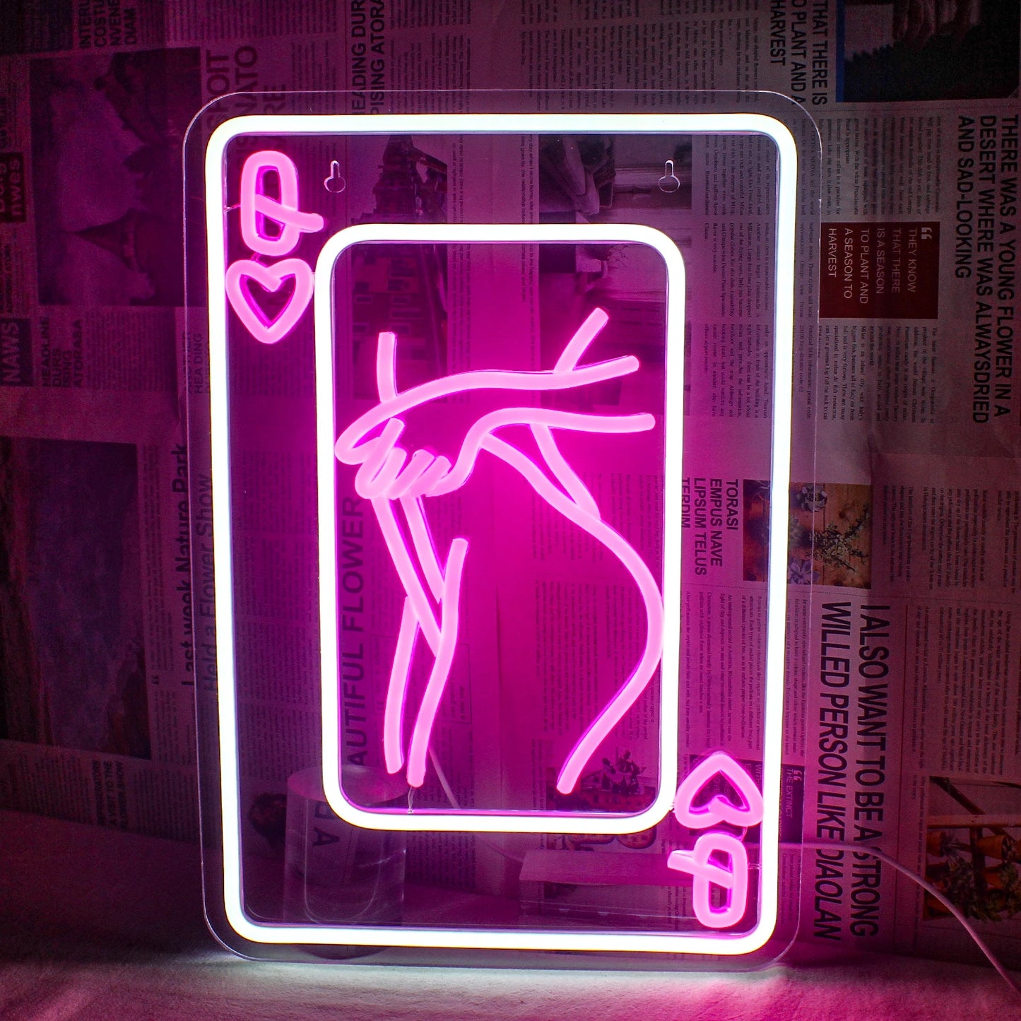 Das Bild zeigt ein LED-Neonschild mit der stilisierten Darstellung einer Frau, die aus Spielkartenelementen besteht.