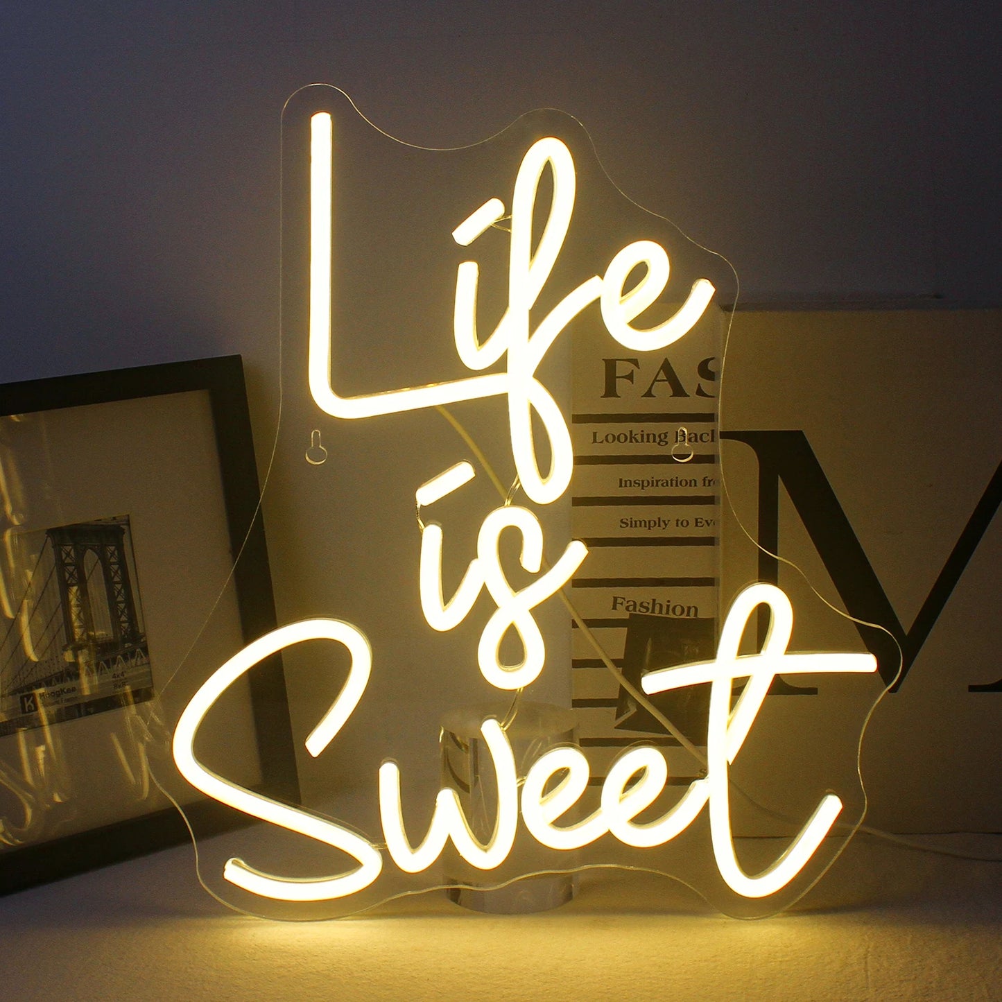 Das Bild zeigt ein lebendiges, handgefertigtes LED-Neonschild in hellen, leuchtenden Farben, auf dem der Satz „Life is Sweet“ steht.