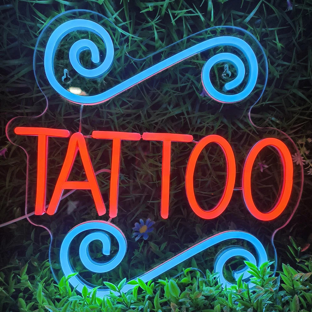 Auf einem beleuchteten LED-Neonschild steht das Wort „TATTOO“ in fetten Großbuchstaben.