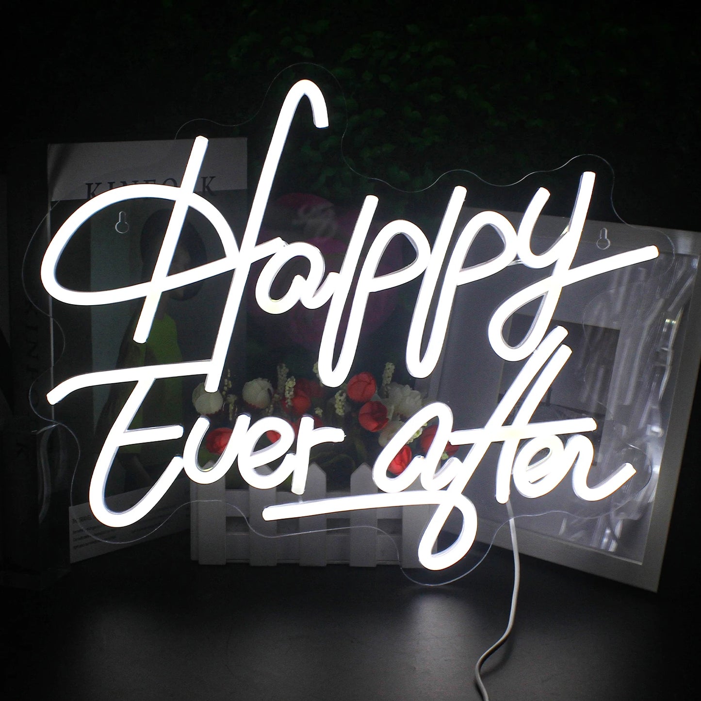 Auf einem leuchtenden LED-Neonschild steht in eleganter Schreibschrift der Satz „Happy Ever After“.