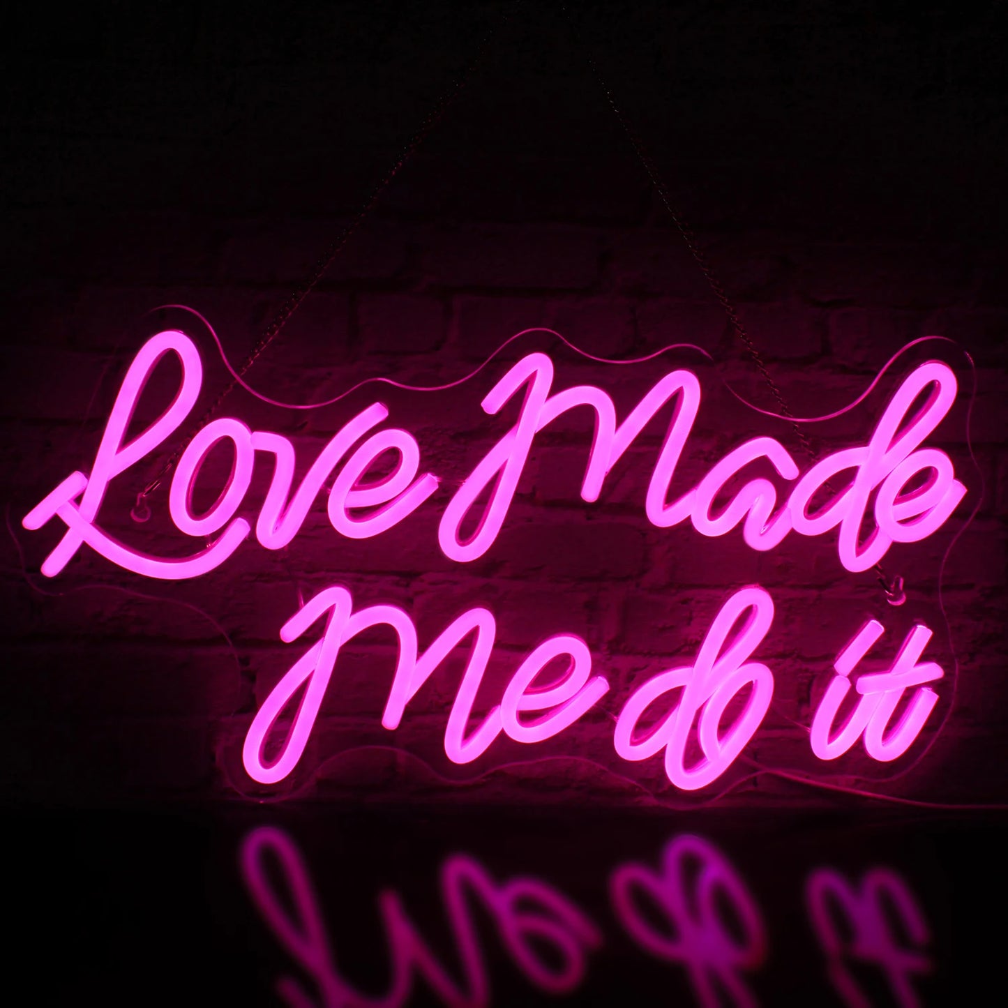 Das Bild zeigt ein leuchtendes LED-Neonschild mit den Worten „Love Made Me Do It“ in einer stilvollen Schreibschrift.
