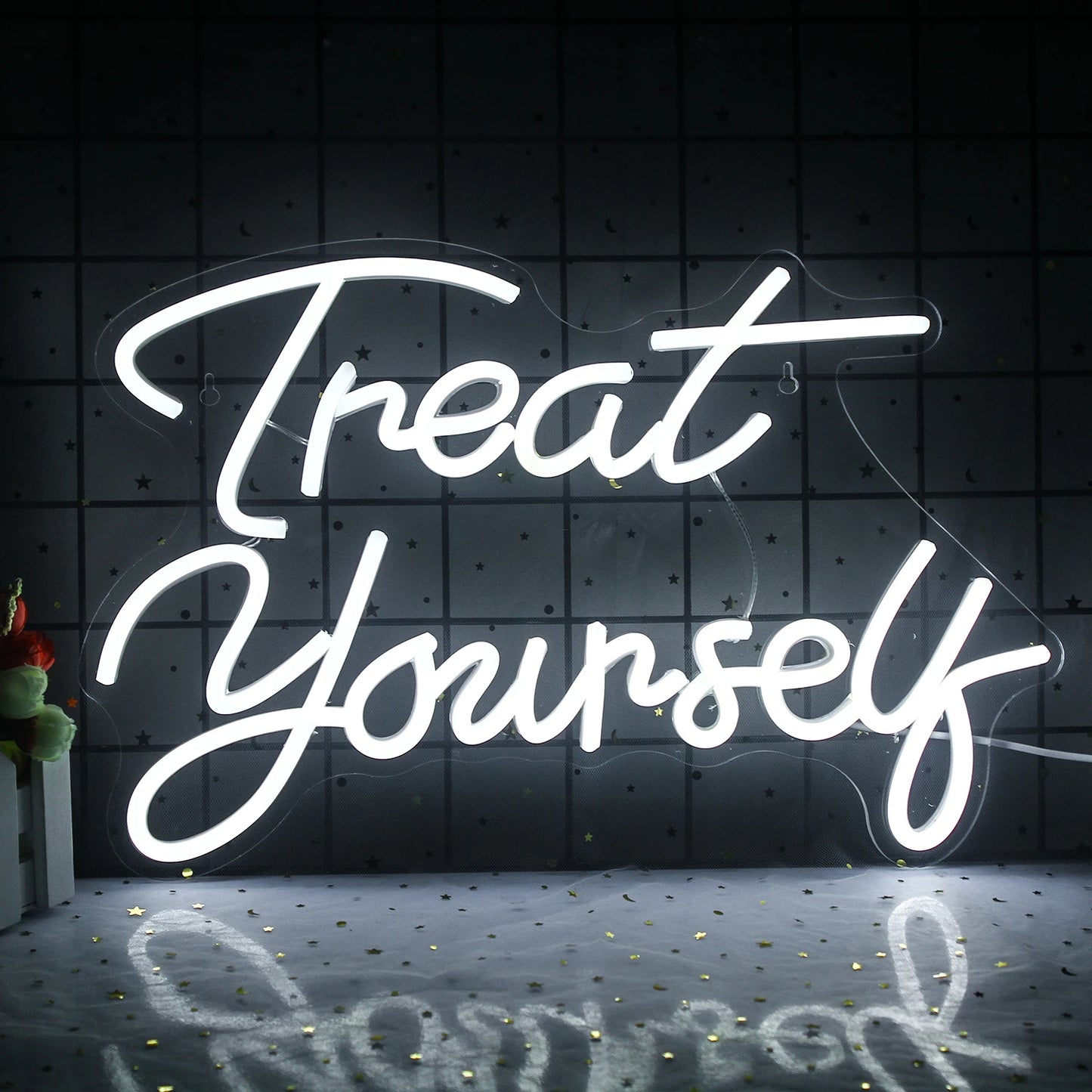 Das Bild zeigt ein leuchtendes LED-Neonschild mit dem Satz „Treat Yourself“ in einer verspielten Schreibschrift.