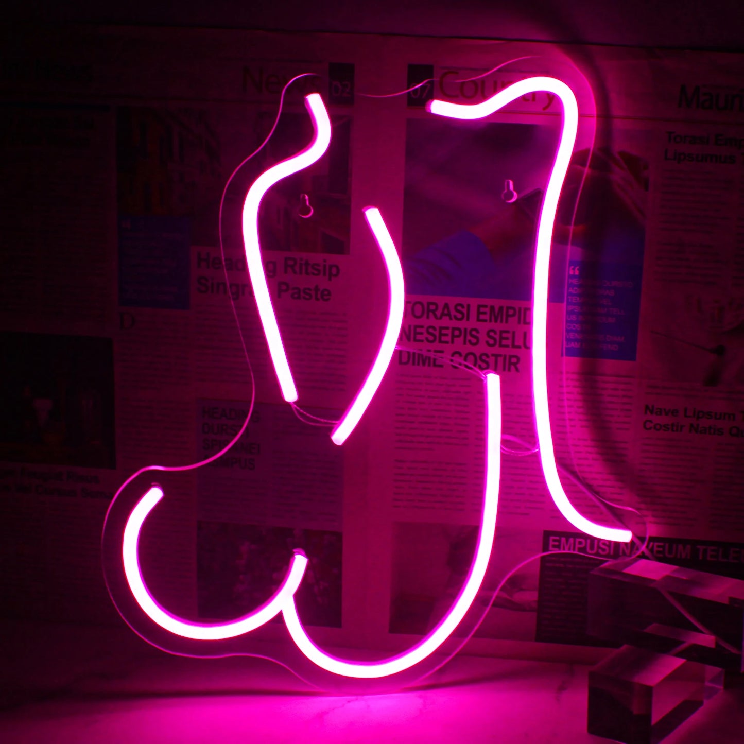 Ein leuchtend pinkes LED-Neonschild in Form der stilisierten Silhouette einer Frau in liegender Position.