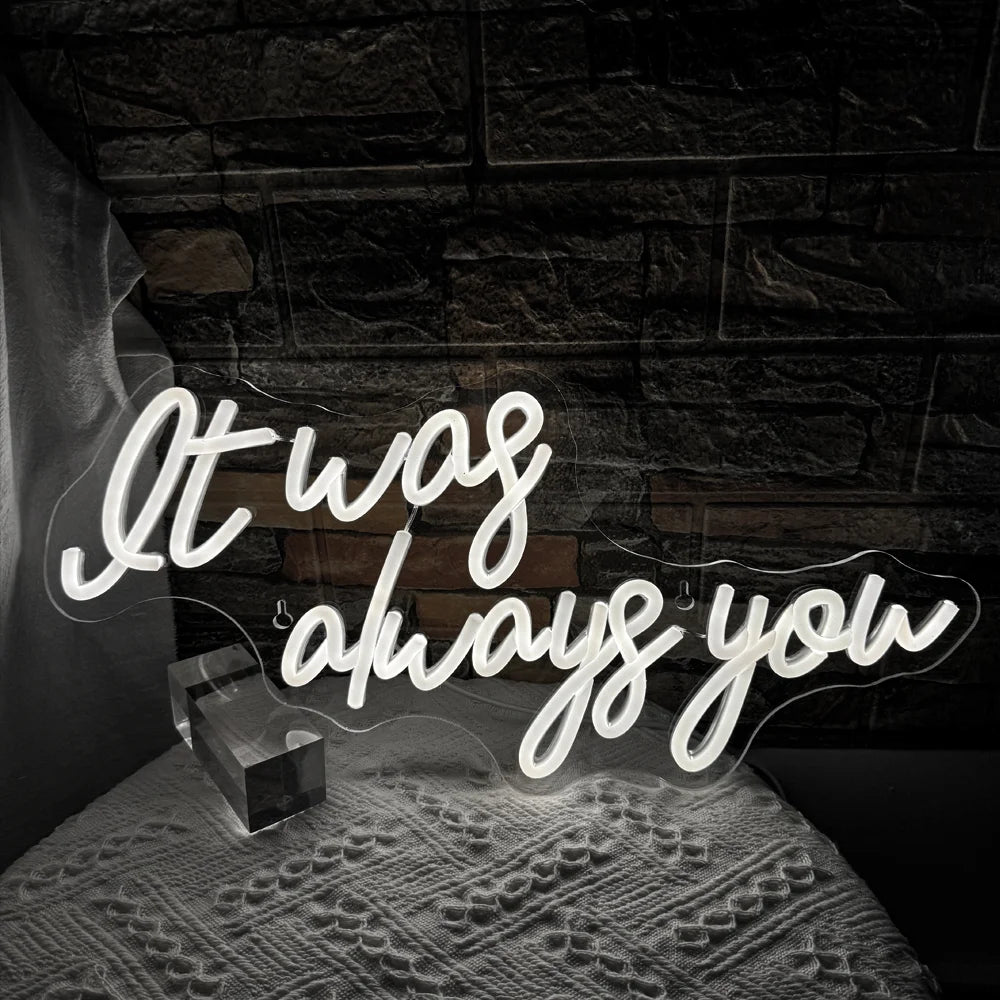 Das Bild zeigt ein leuchtendes LED-Neonschild mit den Worten „It Was Always You“ in einer stilvollen Schreibschrift.