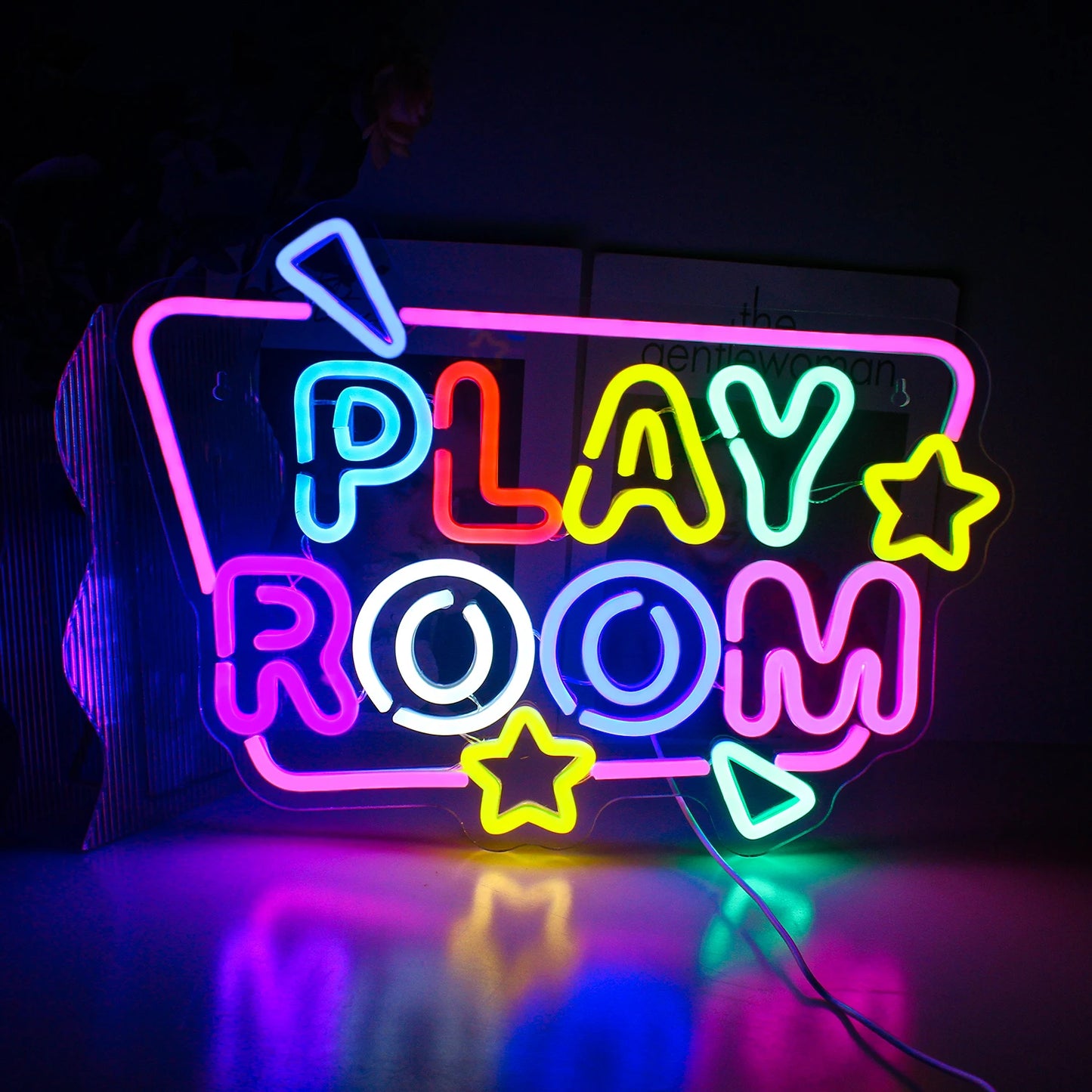 Das Bild zeigt ein leuchtendes LED-Neonschild mit der Aufschrift „Play Room“ in hellen, verspielten Farben.