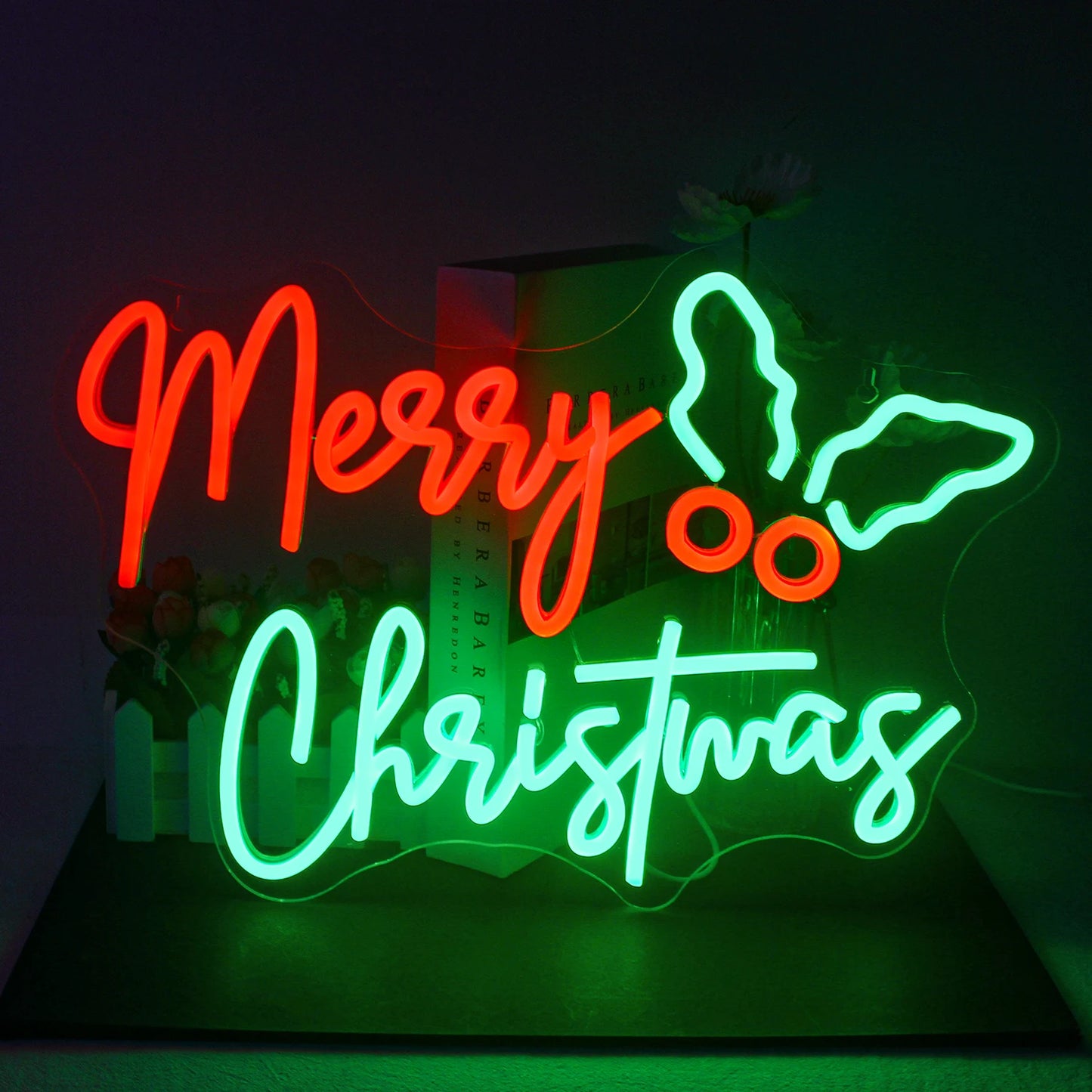 Vor einem dunklen Hintergrund wird ein leuchtendes LED-Neonschild mit der Aufschrift „Frohe Weihnachten“ angezeigt.