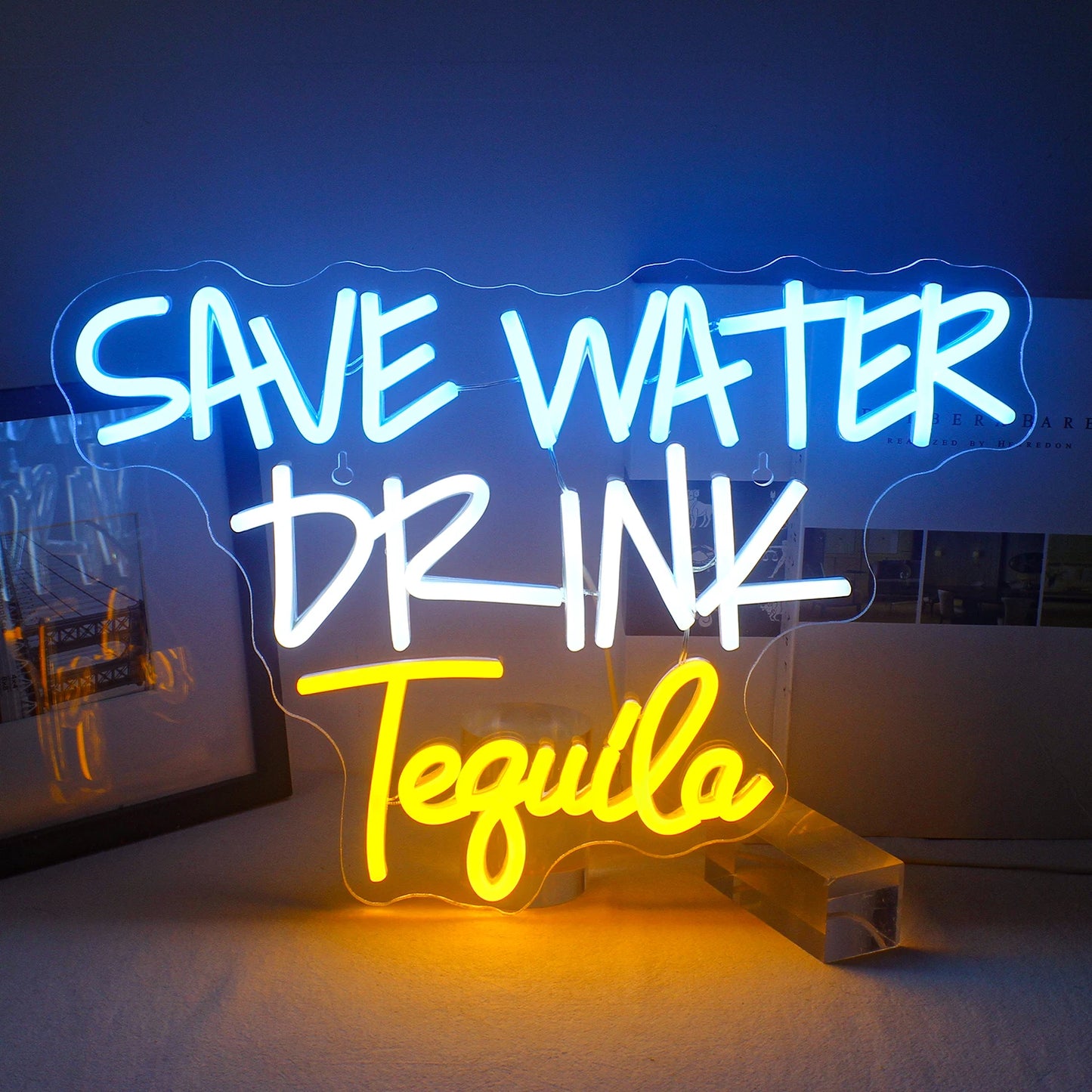 Das Bild zeigt ein leuchtendes LED-Neonschild mit dem Satz „Save Water Drink Tequila“ in kräftiger, verspielter Typografie.
