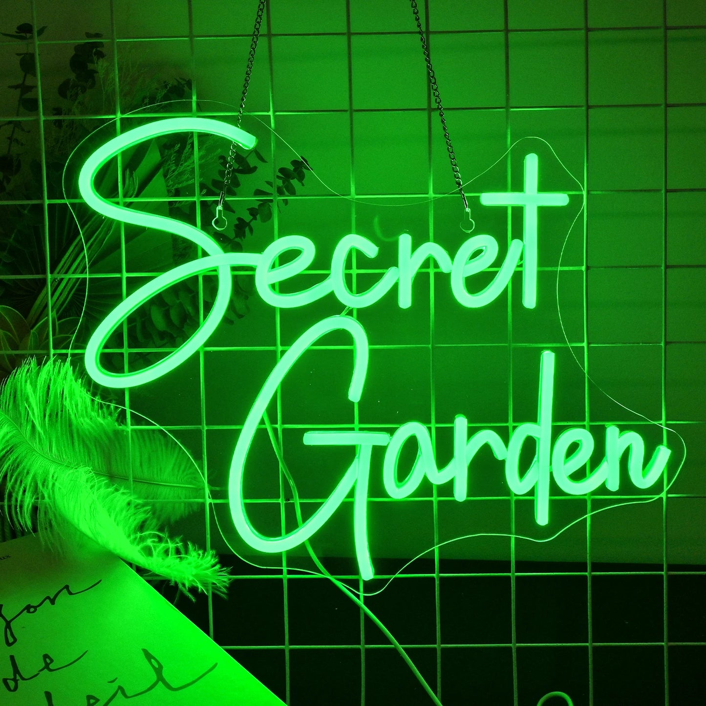 Ein leuchtendes LED-Neonschild mit den Worten „Secret Garden“ in eleganter, kursiver Schrift.