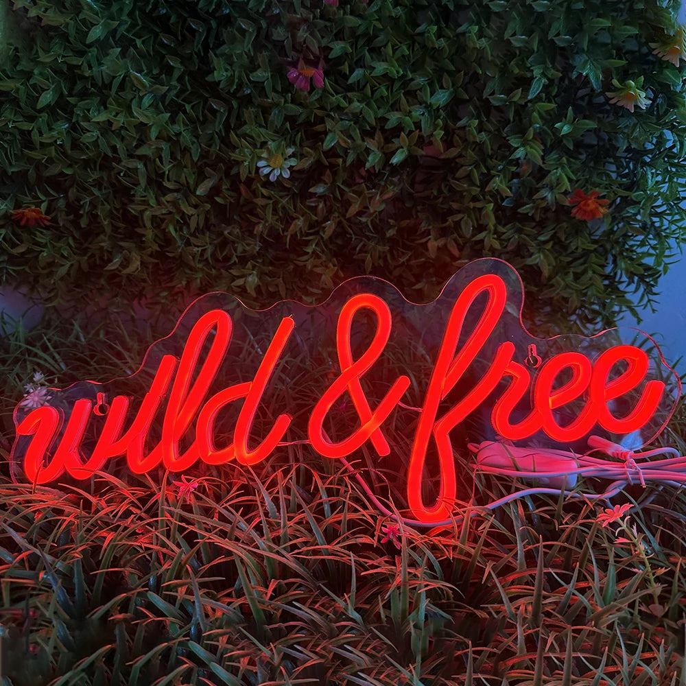 Das Bild zeigt ein leuchtendes LED-Neonschild mit den Worten „Wild & Free“ in einer stilvollen Schreibschrift.