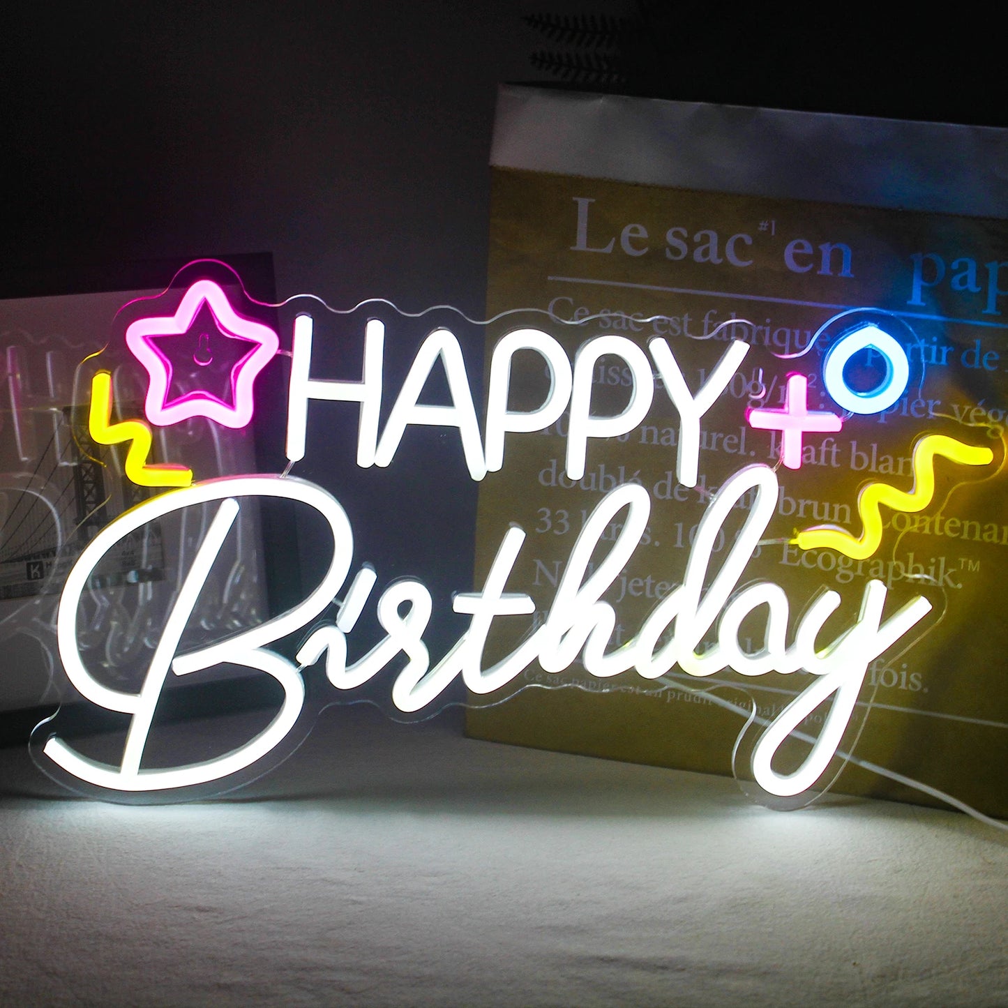 Ein leuchtendes LED-Neonschild mit der Aufschrift „Happy Birthday“ vor dunklem Hintergrund.