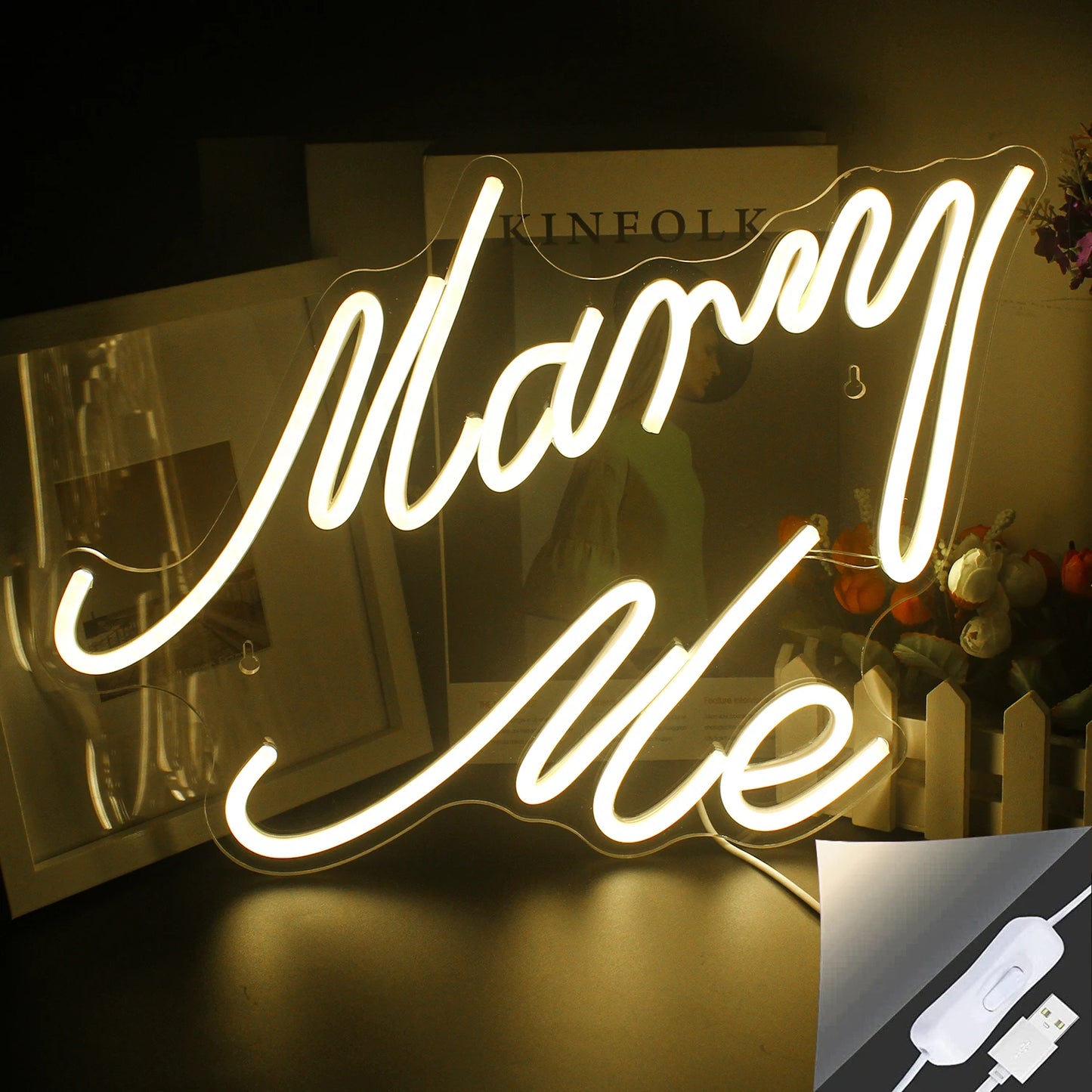 Zu sehen ist ein LED-Neonschild mit der Aufschrift „Heirate mich“, das hell in einem warmen Weißton leuchtet.