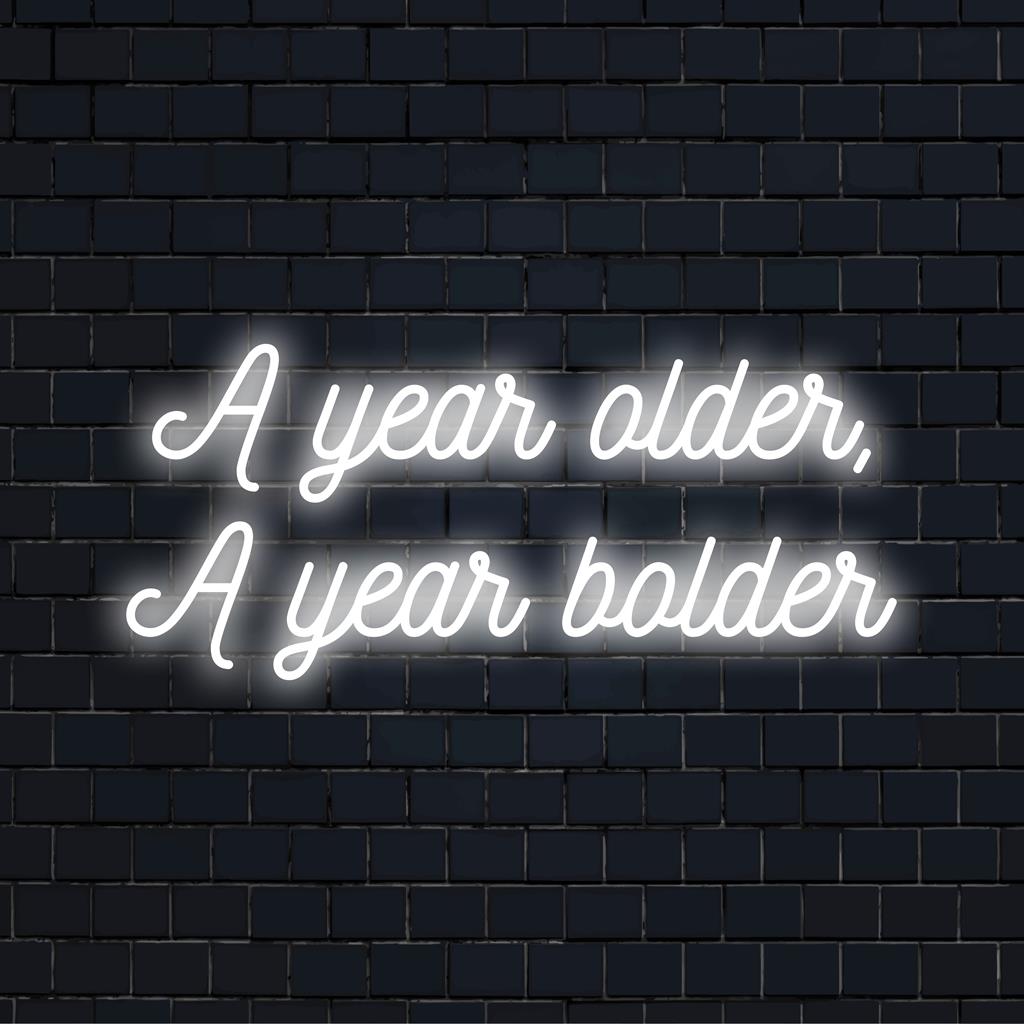 Vibrant LED neon sign reading A Year Older, A Year Bolder as striking neon wall art and custom light decor.