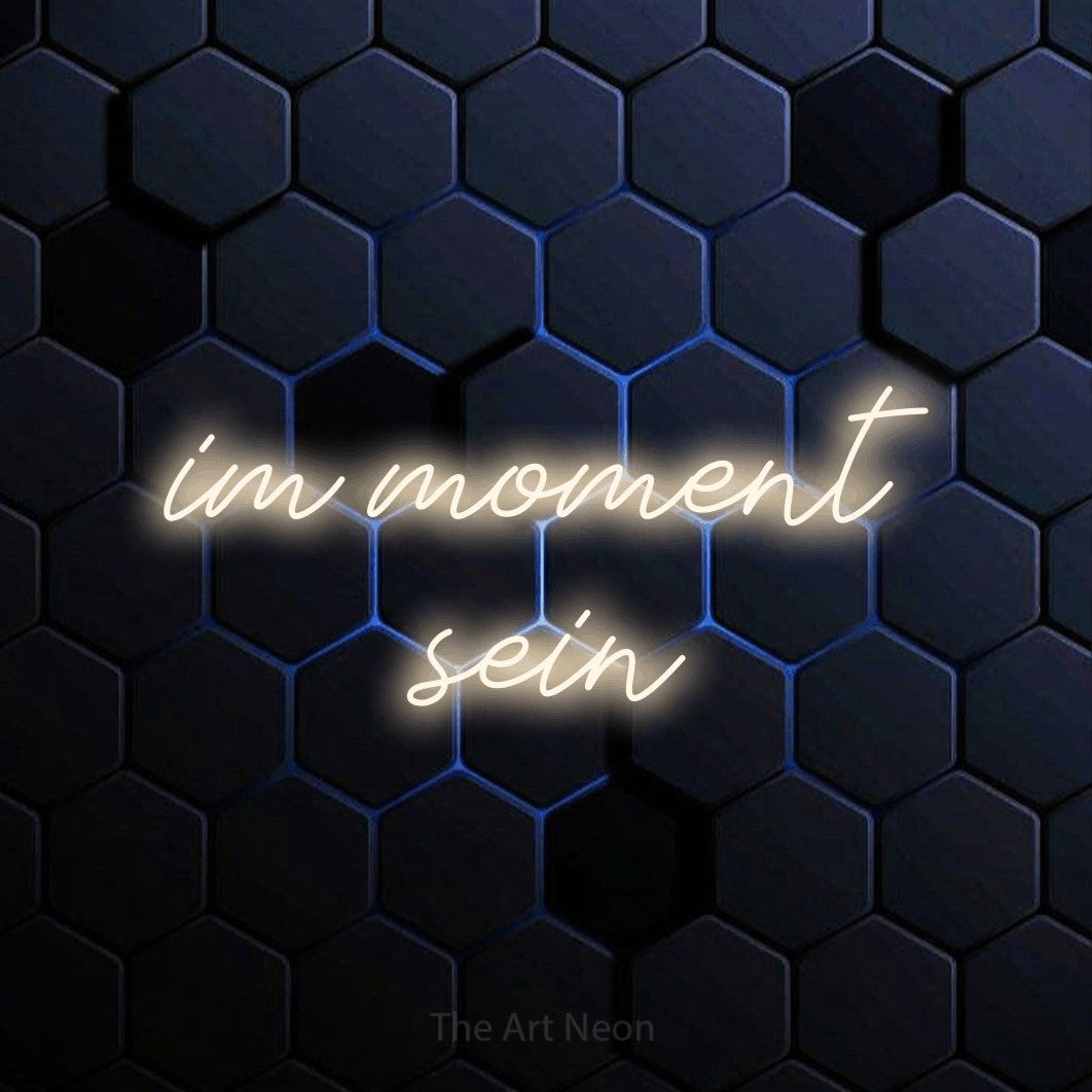 LED neon sign reading “im moment sein”, arranged in 2 lines.