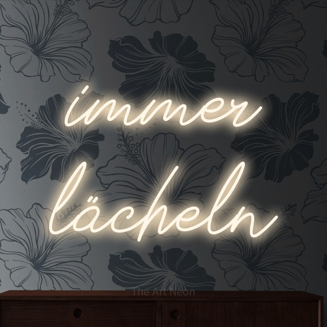 LED neon sign reading “immer lächeln”, arranged in 2 lines.