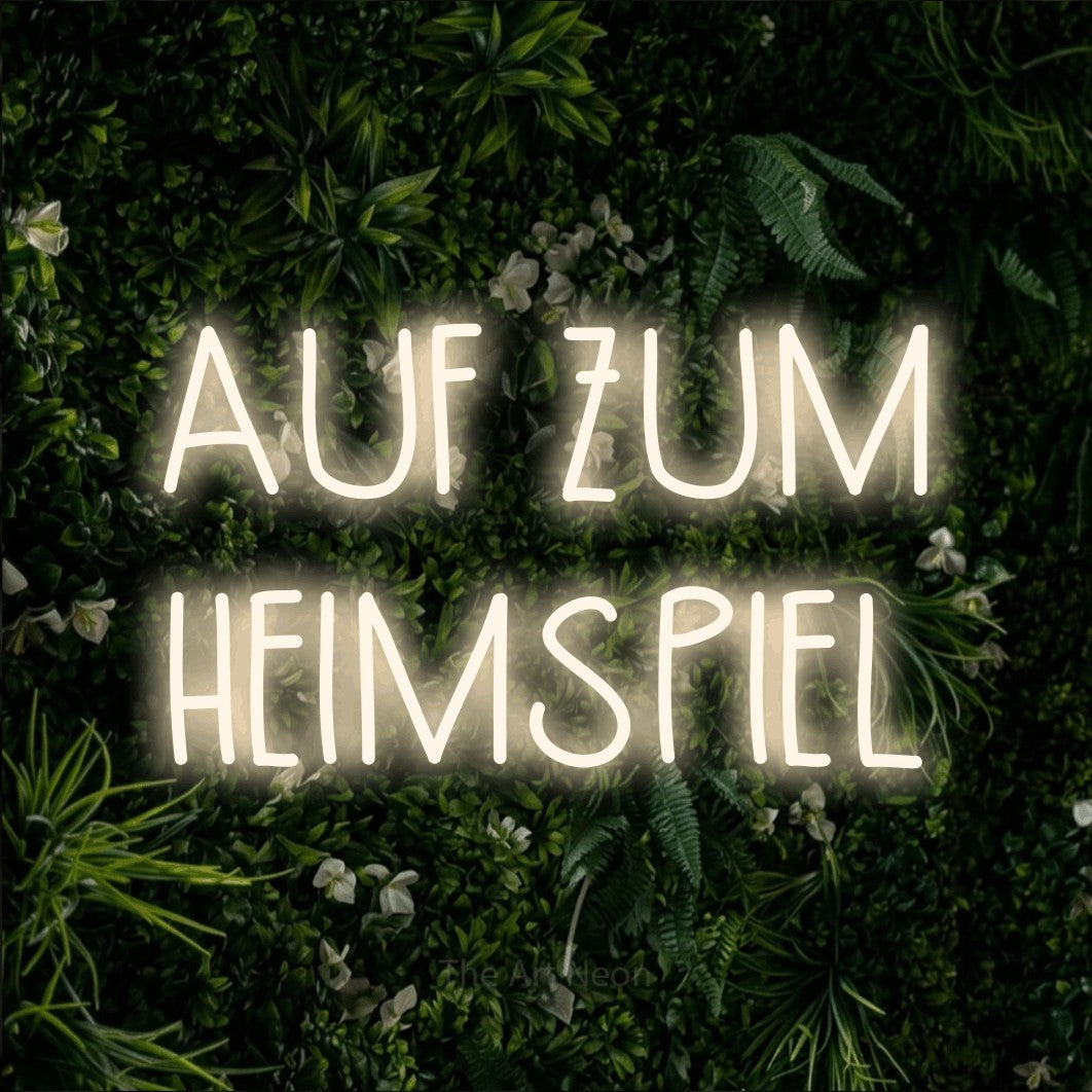 LED neon sign reading “AUF ZUM HEIMSPIEL”, arranged in 2 lines.