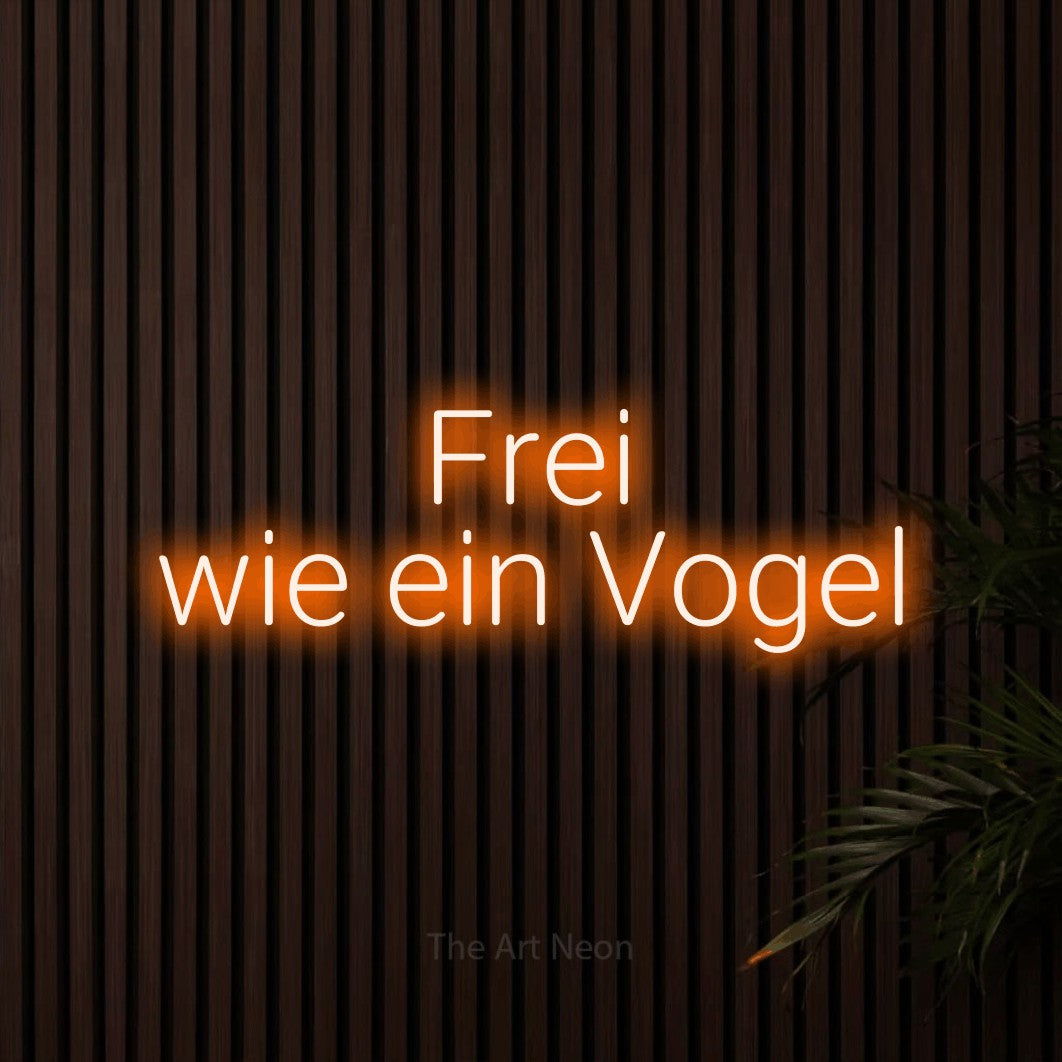 LED neon sign reading “Frei wie ein Vogel”, arranged in 2 lines.
