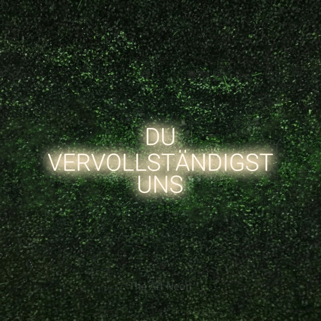 LED neon sign reading “DU VERVOLLSTÄNDIGST UNS”, arranged in 3 lines.