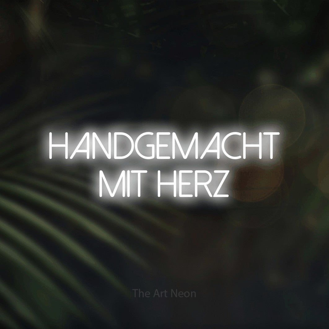 LED neon sign reading “HANDGEMACHT MIT HERZ”, arranged in 2 lines.