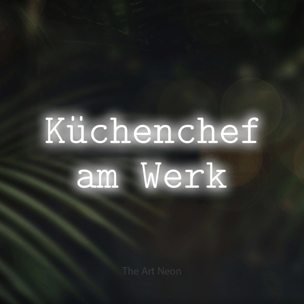 LED neon sign reading “Küchenchef am Werk”, arranged in 2 lines.