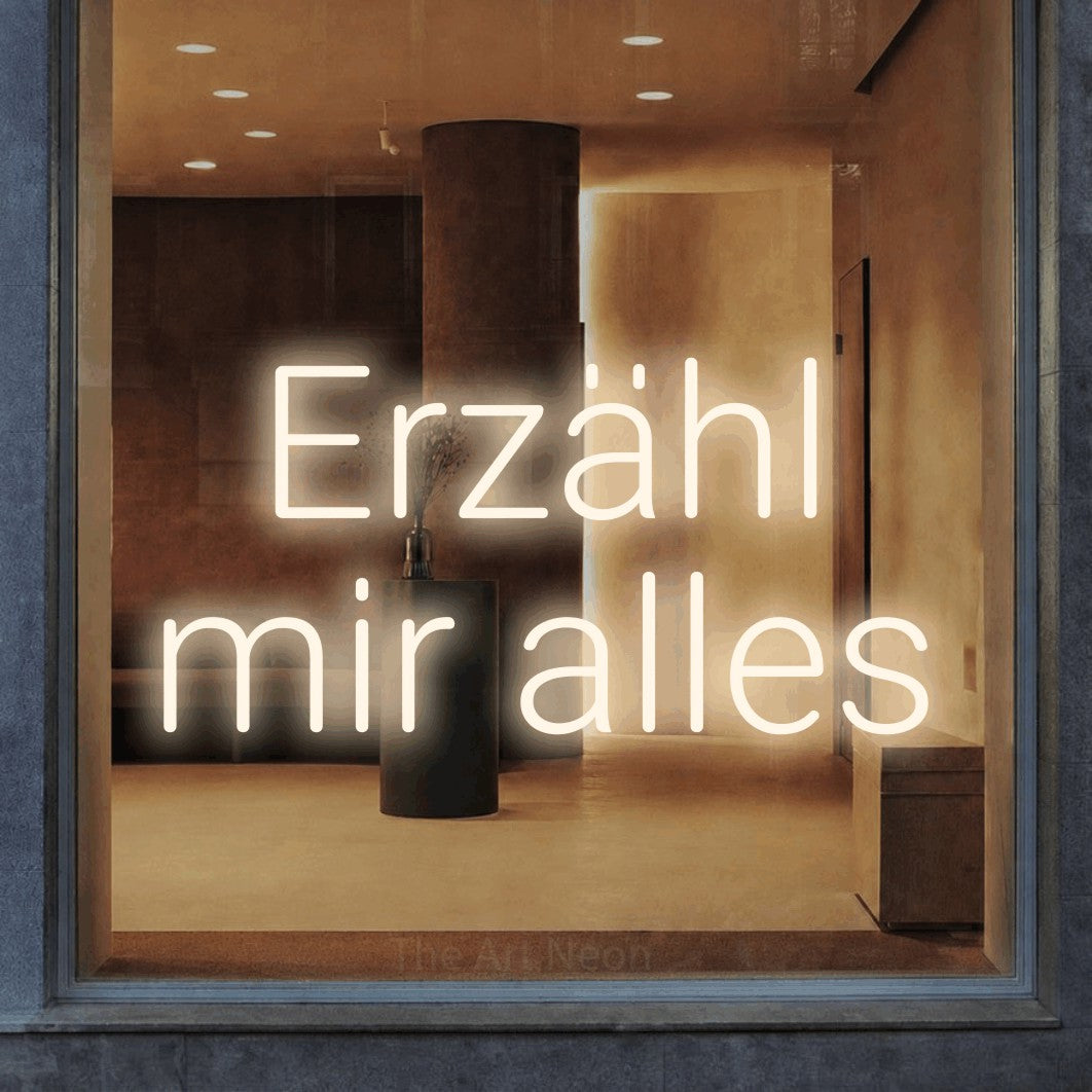 LED neon sign reading “Erzähl mir alles”, arranged in 2 lines.