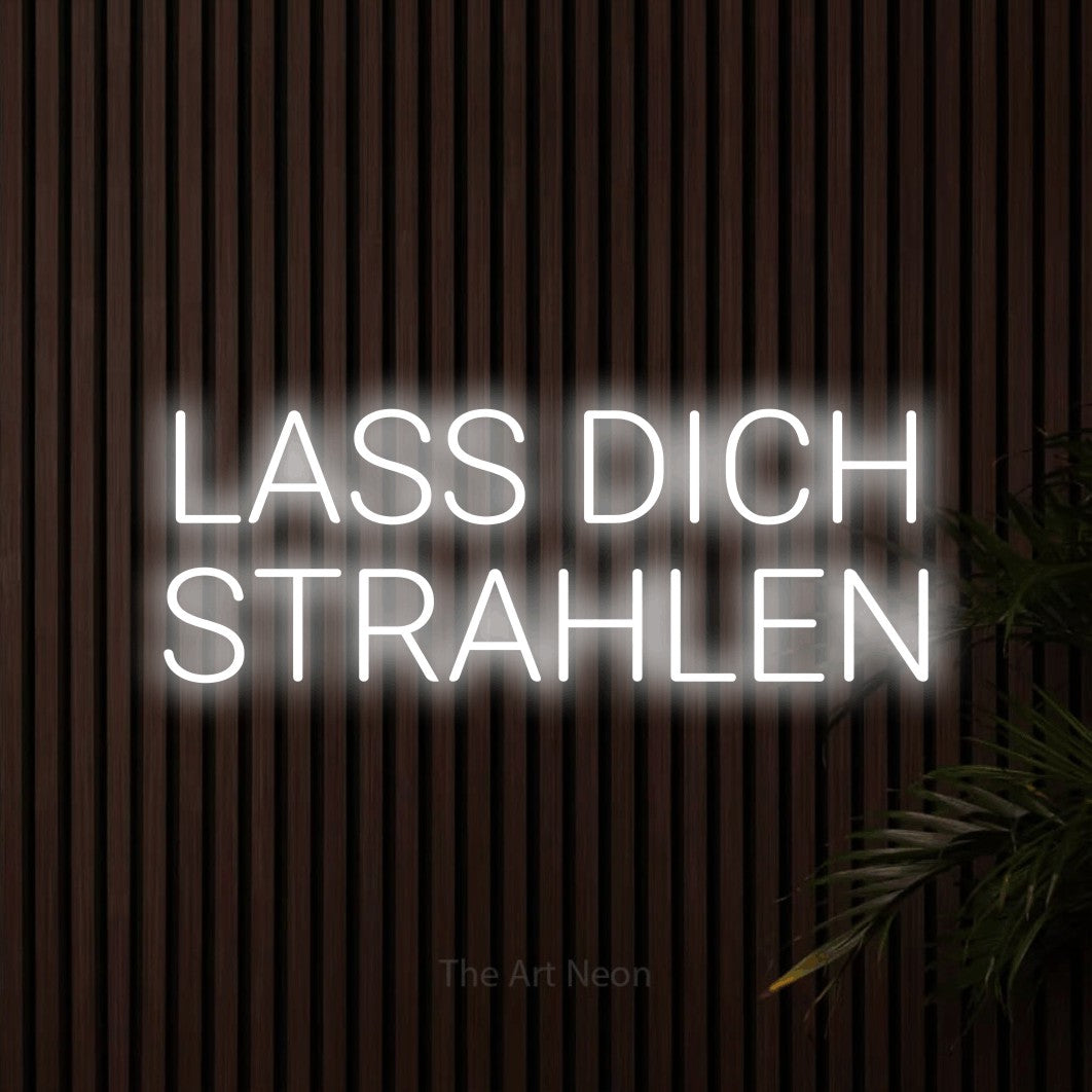LED neon sign reading “LASS DICH STRAHLEN”, arranged in 2 lines.