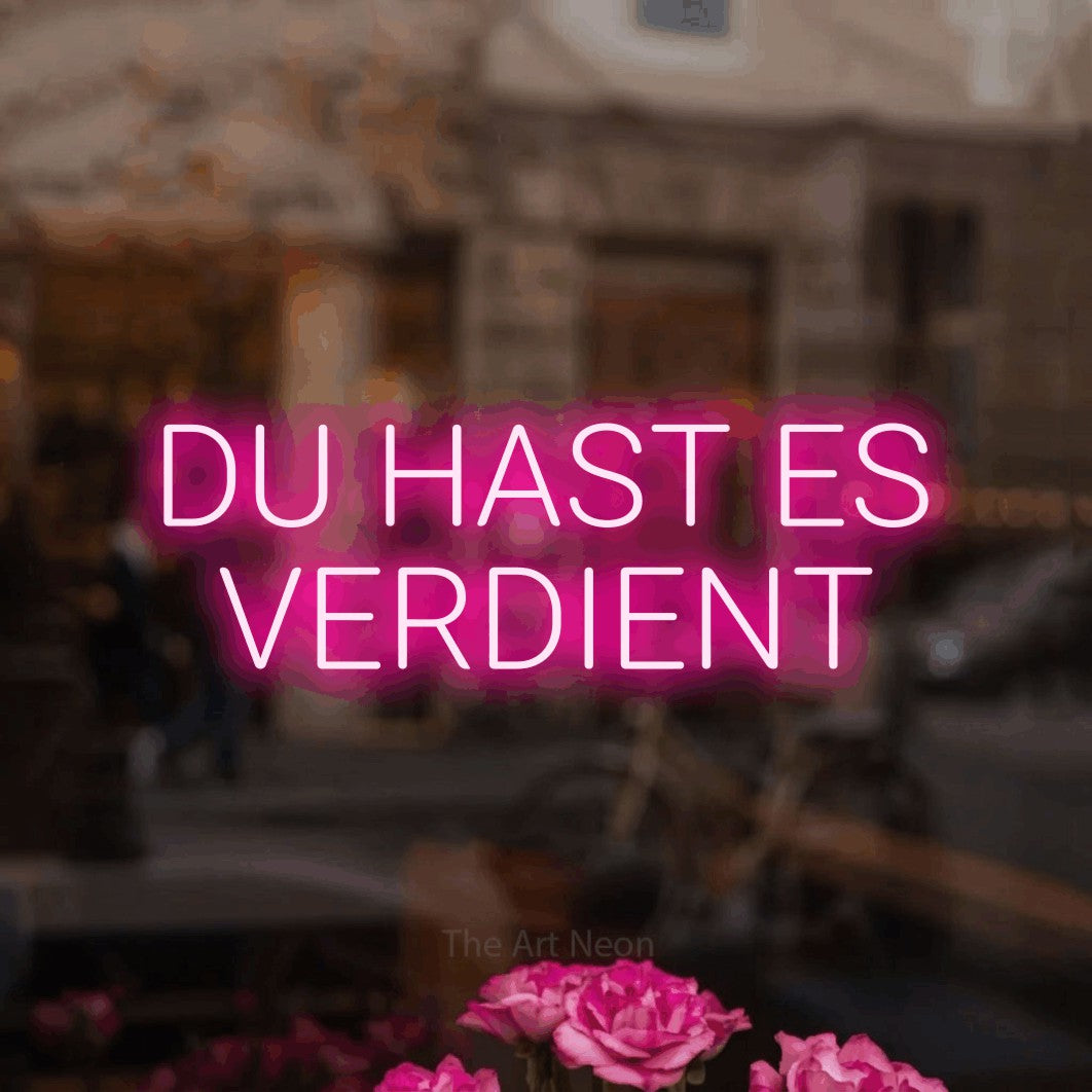 LED neon sign reading “DU HAST ES VERDIENT”, arranged in 2 lines.