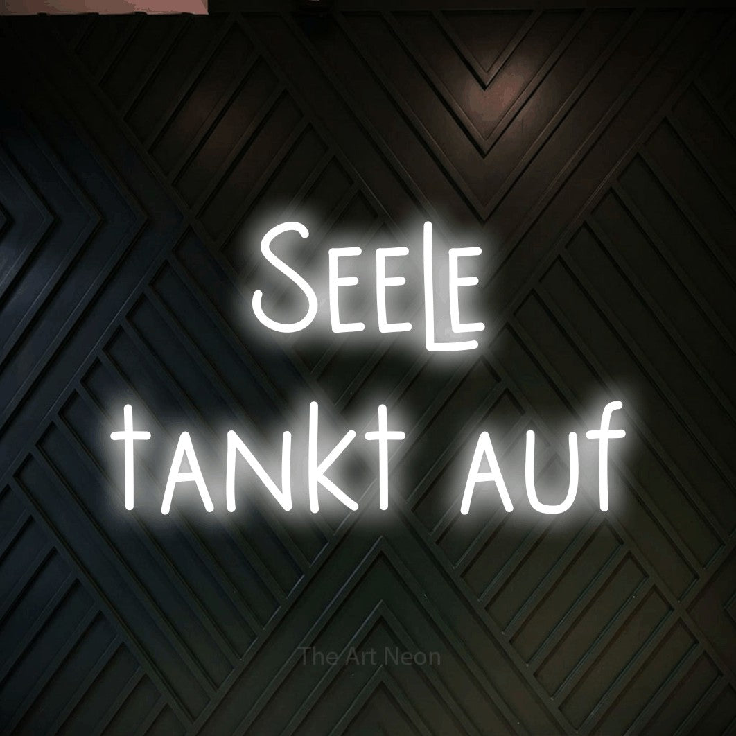 LED neon sign reading “Seele tankt auf”, arranged in 2 lines.