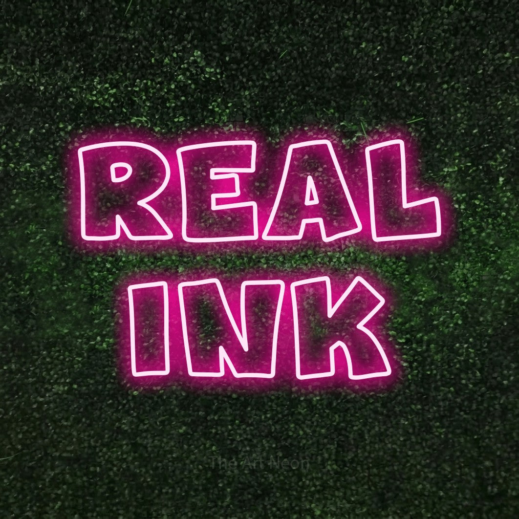 LED neon sign reading “Real Ink”, arranged in 2 lines.