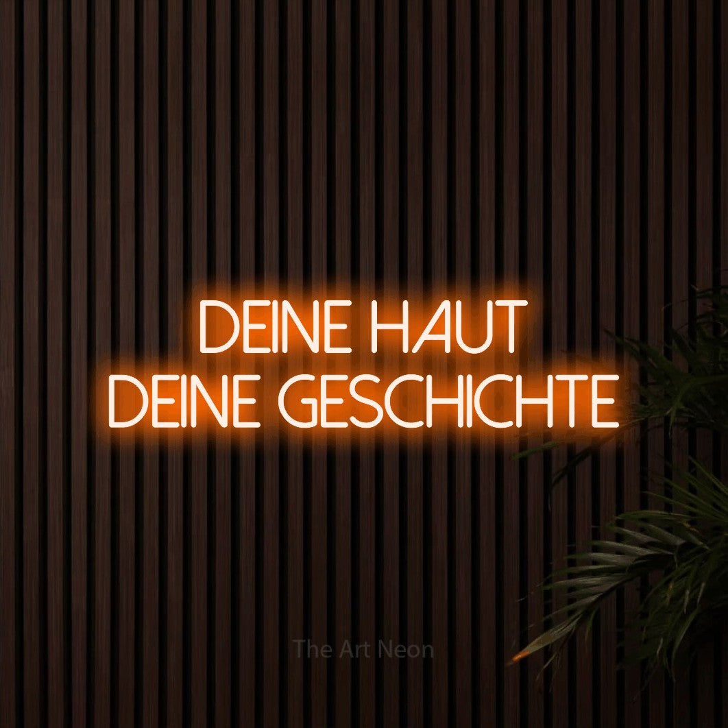 LED neon sign reading “deine haut deine GESCHICHTE”, arranged in 2 lines.