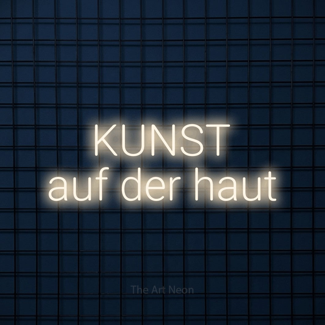 LED neon sign reading “KUNST auf der haut”, arranged in 2 lines.