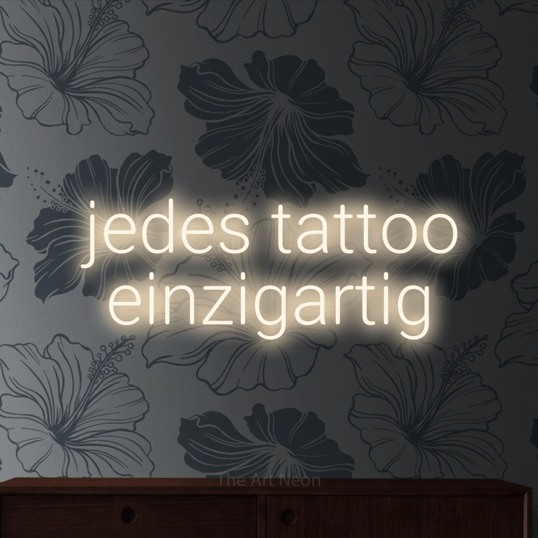 LED neon sign reading “jedes tattoo einzigartig”, arranged in 2 lines.